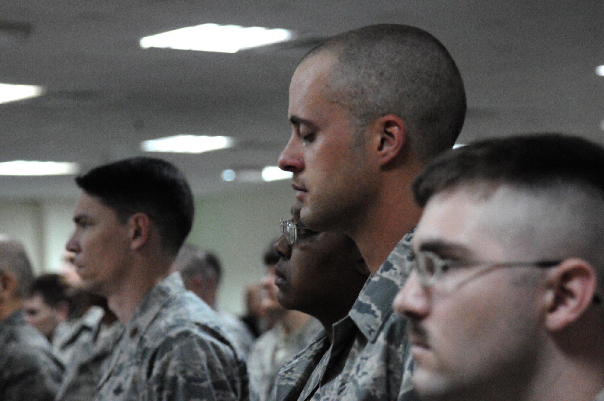 Members of the 386th Expeditionary Communications Squadron stand at attention while "Taps" play during a memorial service March 19, at an undisclosed location in Southwest Asia. The 386th Air Expeditionary Wing held a memorial service to remember the life of Senior Airman Michael J. Hinkle II, 24, who died from a non-combat related incident March 16. (U.S. Air Force photo by Staff Sgt. Patrice Clarke)