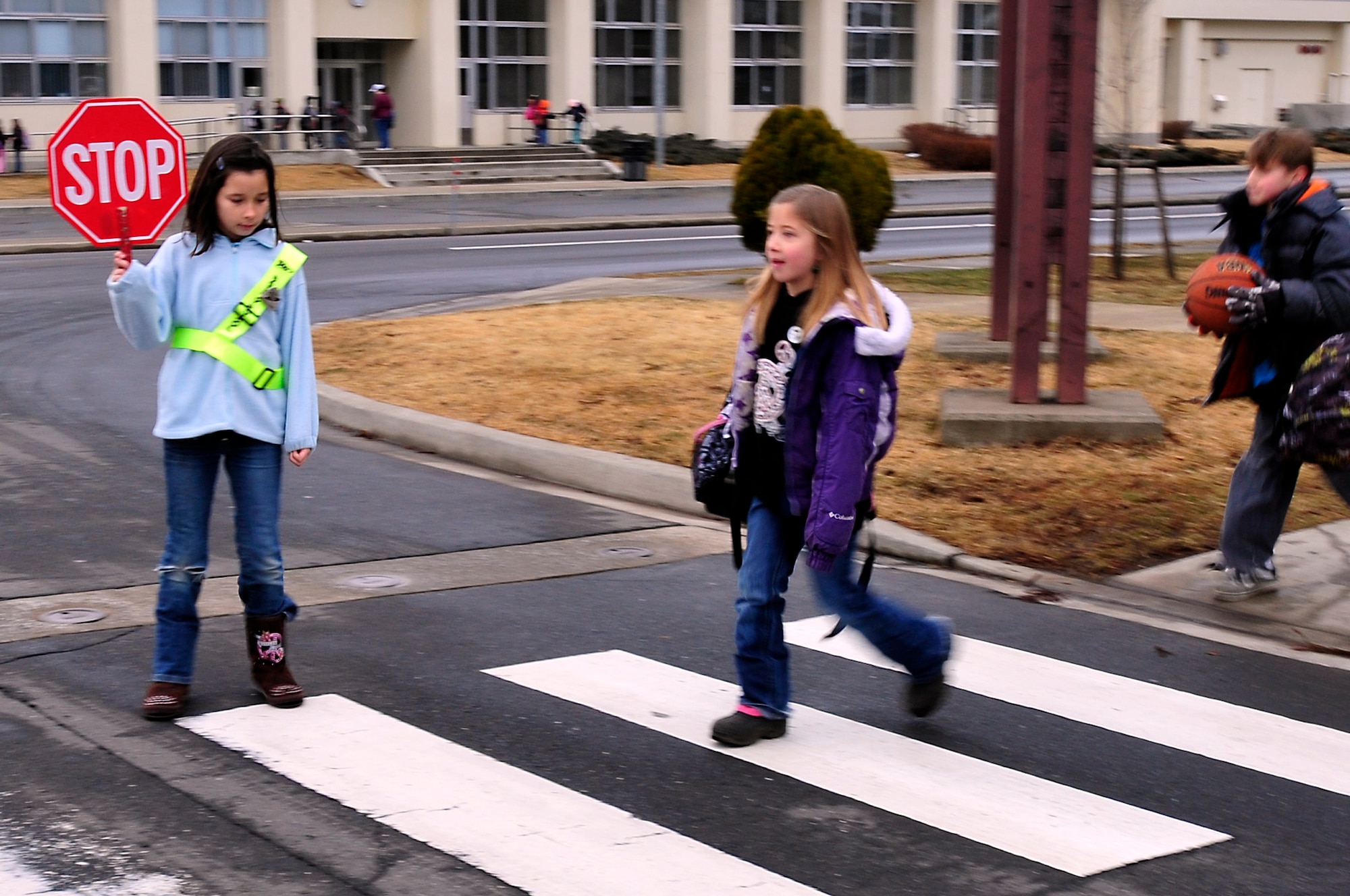 MISAWA AIR BASE, Japan -- Ten-year-old Samantha Browning, safety patrol, stops traffic to allow students to safely cross the street Mar. 21. Safety patrol is a volunteer program for fourth, fifth and sixth graders to raise and lower the flags and ensure the safety of younger children as they cross the street at the crosswalks. (U.S. Air Force photo by Staff Sgt. Marie Brown\Released)
