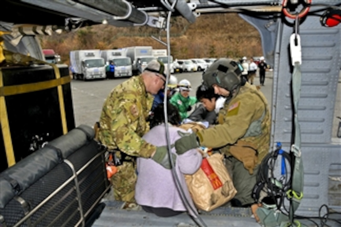 A U.S. Air Force search and rescue airman (right) assists a Japanese disaster medical assistance team to off-load an earthquake victim from an HH-60G Pave Hawk helicopter in Sendai, Japan, on March 14, 2011.  