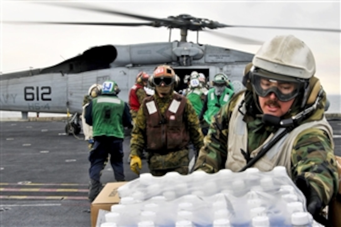 U.S. sailors and Marines aboard the aircraft carrier USS Ronald Reagan load humanitarian assistance supplies onto an HH-60H Seahawk helicopter assigned to Anti-Submarine Squadron 4 in the Pacific Ocean on March 19, 2011.  The Ronald Reagan is operating off the coast of Japan providing humanitarian assistance to support Operation Tomodachi.  DoD photo by Seaman Nicholas A. Groesch, U.S. Navy.  (Released)