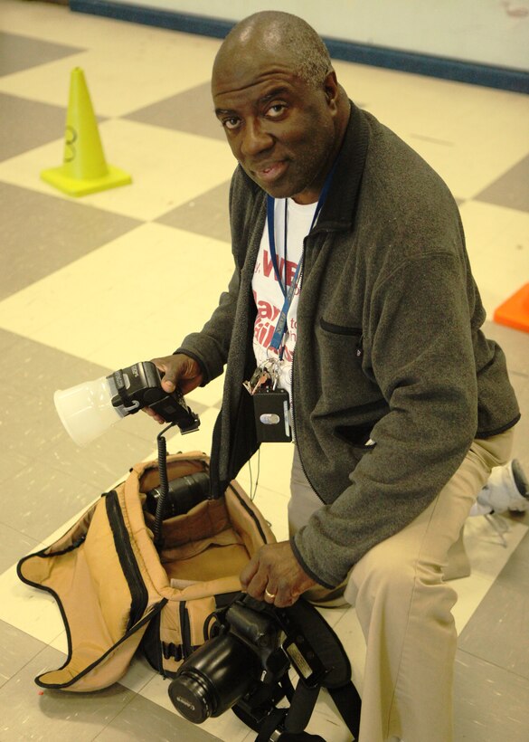 Retired Gunnery Sgt. Johnny M. White, a custodian at the Tarawa Terrace I Primary School and member of the Professional Photographers of North Carolina, takes a moment to pose while assembling his camera gear, at the primary school, March 22.