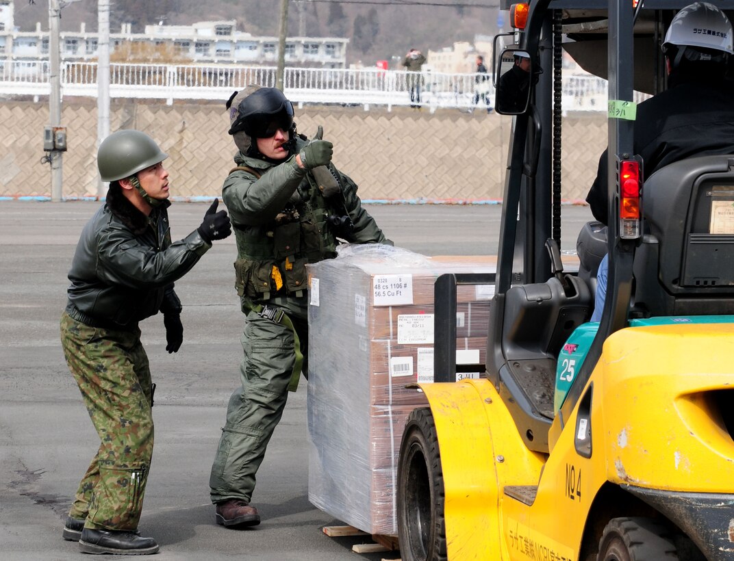 Gunnery Sgt. Sam Carnes, right, and a member of the Japan Maritime Self-Defense Force direct the movement of humanitarian assistance and disaster relief supplies unloaded from a CH-46E Sea Knight helicopter assigned to Marine Medium Helicopter Squadron 262. The forward-deployed amphibious assault ship USS Essex, USS Harpers Ferry (LSD 49) and USS Germantown (LSD 42) with the embarked 31st Marine Expeditionary Unit are currently operating off the coast of Hachinohe in northeastern Japan in support of Operation Tomodachi.