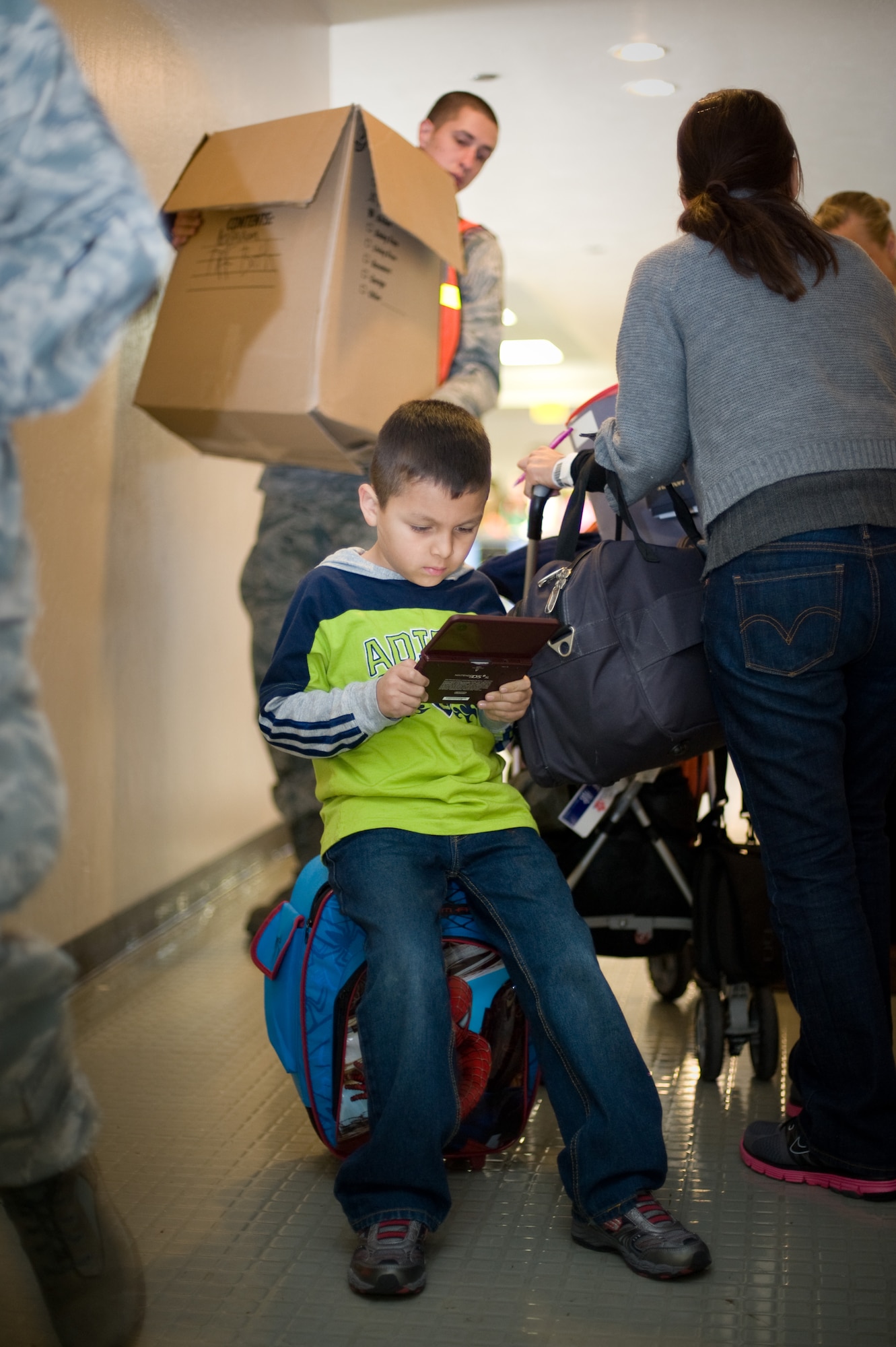 Six-year-old Adam Falcon plays with his Gameboy as his mother is helped by Air Force members at the Travis AFB passenger terminal on March 22. The Falcons were part of approximately 240 military  family members who returned to the U.S. from Japan following the March 11, 2011 earthquake and tsunami that hit the island nation. (Photo by Ken Wright)