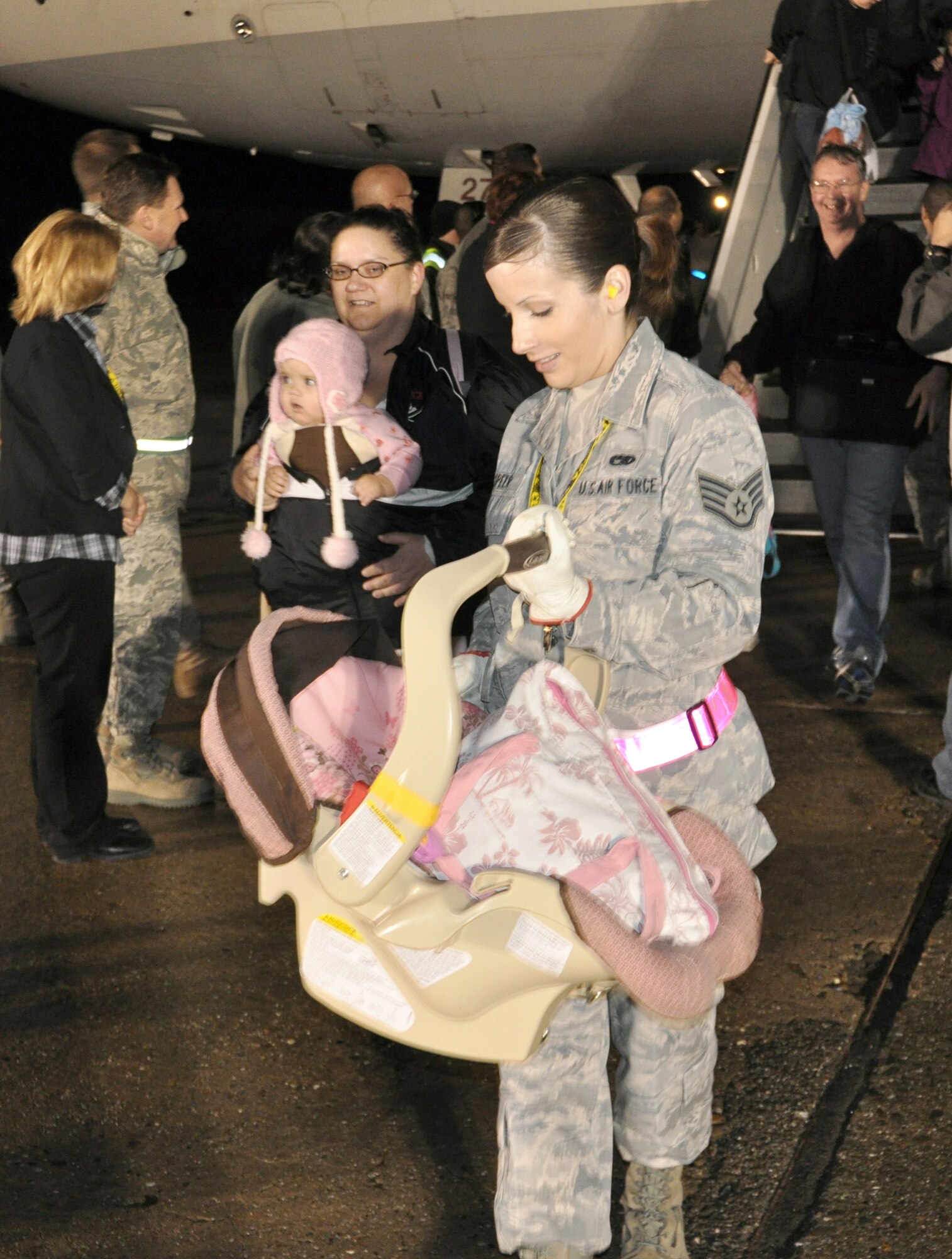 Staff Sgt. Katie Speer carries a child off a military-chartered flight March 22, 2011, at Travis Air Force Base, Calif. Approximately 500 passengers arrived at Travis AFB in support of Operation Pacific Passage. On March 17, 2011, the Office of the Secretary of Defense approved voluntary assisted departures to the United States for family members residing in Japan. These flights will continue for the foreseeable future to accommodate the needs of our service member's families. Sergeant Speer is the 60th Air Mobility Wing command chief executive. (U.S. Air Force photo/Airman 1st Class Michael Battles)
