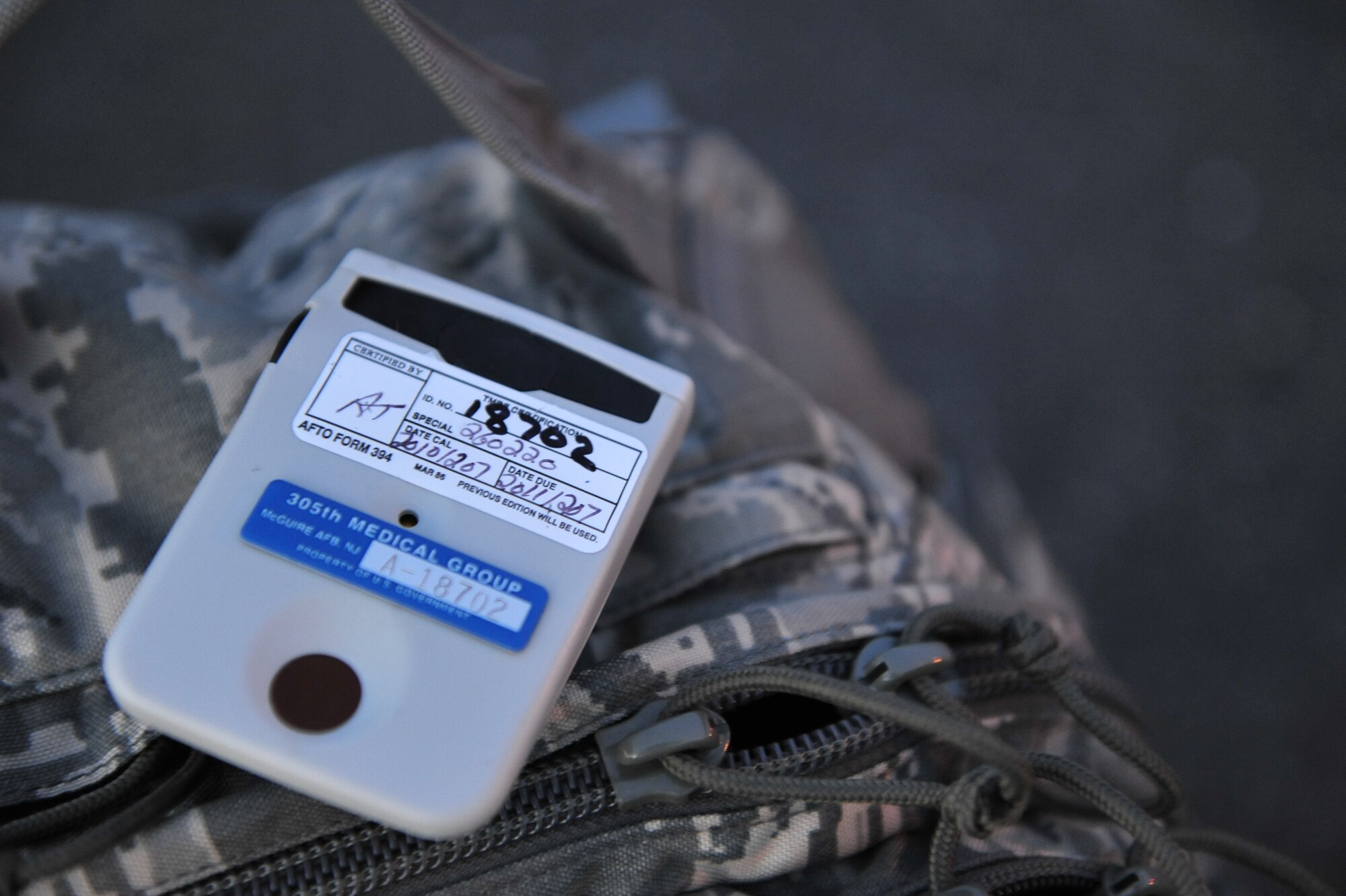A radiation dosimeter sits on the mobility bag of a deploying 621st Contingency Response Wing airfield assessment team member.  Each deploying Airman was issued a personal dosimeter to track their exposure while conducting airfield assessments at locations around Japan. (U.S. Air Force photo by Tech. Sgt. Parker Gyokeres/released)