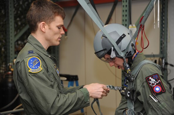 Capt. James White, 509th Operations Support Squadron aircrew flight equipment officer, assists Andrew Swan with his harness during egress training at Whiteman Air Force Base March 19. Andrew visited Whiteman to be an Airman for a day as part of a Dream Factory project. (U.S. Air Force photo by Staff Sgt. Lauren Padden)(Released) 
