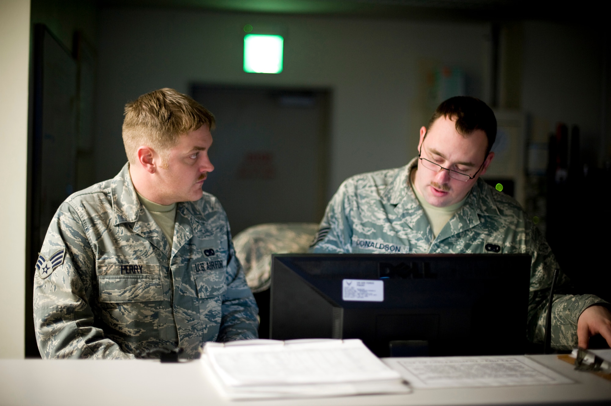 YOKOTA AIR BASE, Japan -- Staff Sgt. Justin Donaldson and Senior Airman Anthony Perry, 374th Logistics Readiness Squadron vehicle dispatch operators, discuss daily operations here March 23. In the last two weeks, LRS has tripled their efforts, to include shuttle bus operations and issuing government vehicles to units that have acquired additional personnel in part of the relief effort. (U.S. Air Force photo/Staff Sgt. Chad Strohmeyer)