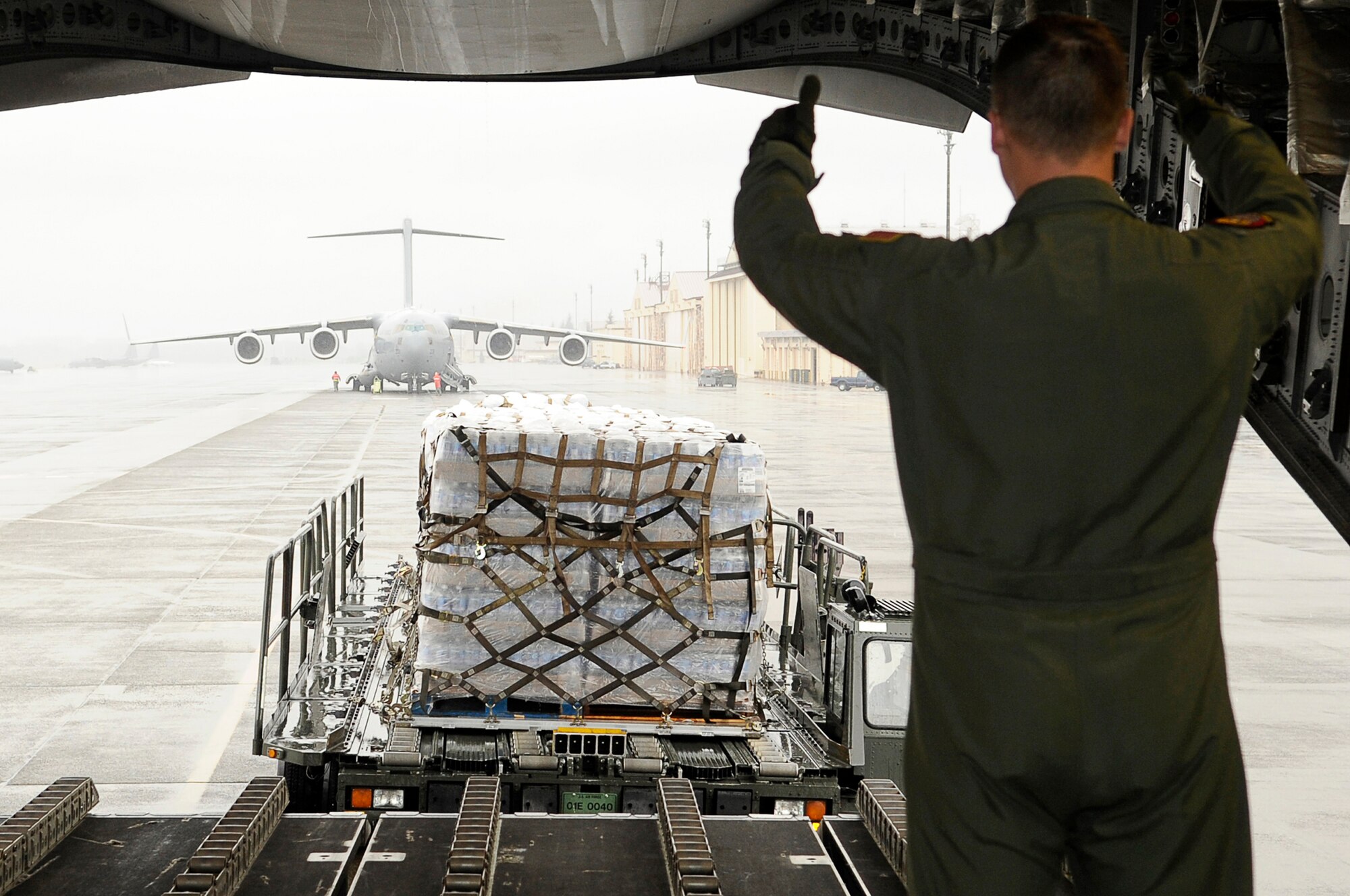 As part of Operation Tomodachi, Staff Sgt. Chris Baker guides a K-loader with humanitarian supplies behind a C-17 Globemaster III March 21, 2011, at Yokota Air Base, Japan. Crews unloaded the water and other relief items at Sendai Airport as American forces worked with their Japanese counterparts to aid the people of Japan in the aftermath of an  earthquake that hit Japan March 11. "Tomodachi" is a Japanese word meaning friends. Sergeant Baker is a member of the 535th Airlift Squadron at Joint Base Pearl Harbor-Hickam, Hawaii. (U.S. Air Force photo by/Master Sgt. Jeromy K. Cross) 
