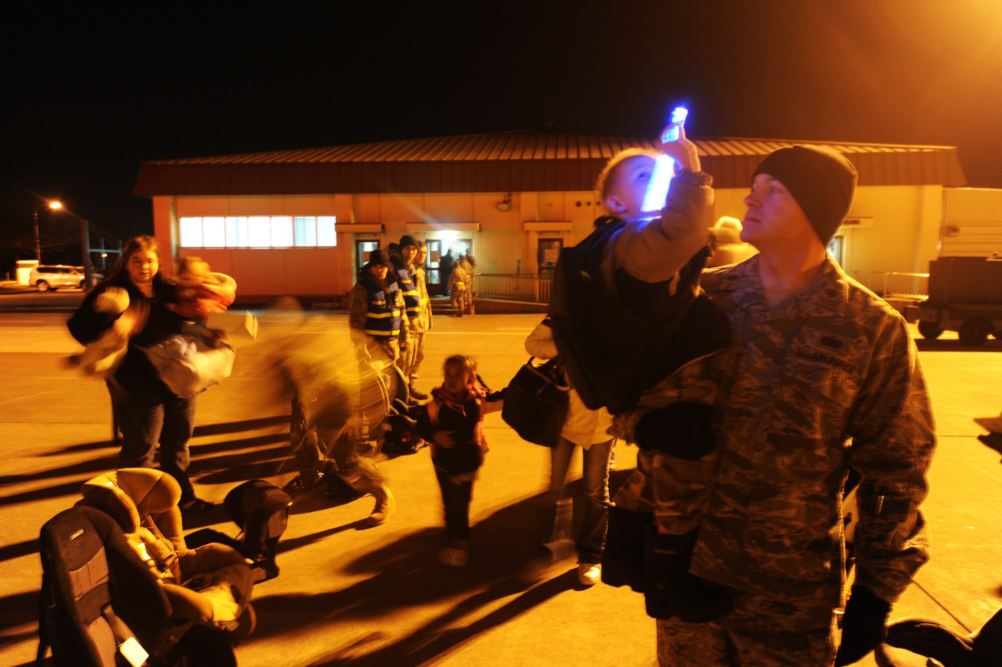 MISAWA AIR BASE, Japan -- During the boarding of the voluntary family departure Maj. Andrew Pate, 35th Logistics Readiness Squadron commander, helps out mother Ruth Finstuen by holding her son David, age 3, while she locates her 1-year-old daughter Kristiana's car seat March 22. The Defense Department authorized a voluntary departure of family members from Northern Japan due to the recent earth quake and tsunami disaster.  (U.S. Air Force Staff Sgt. April Quintanilla)