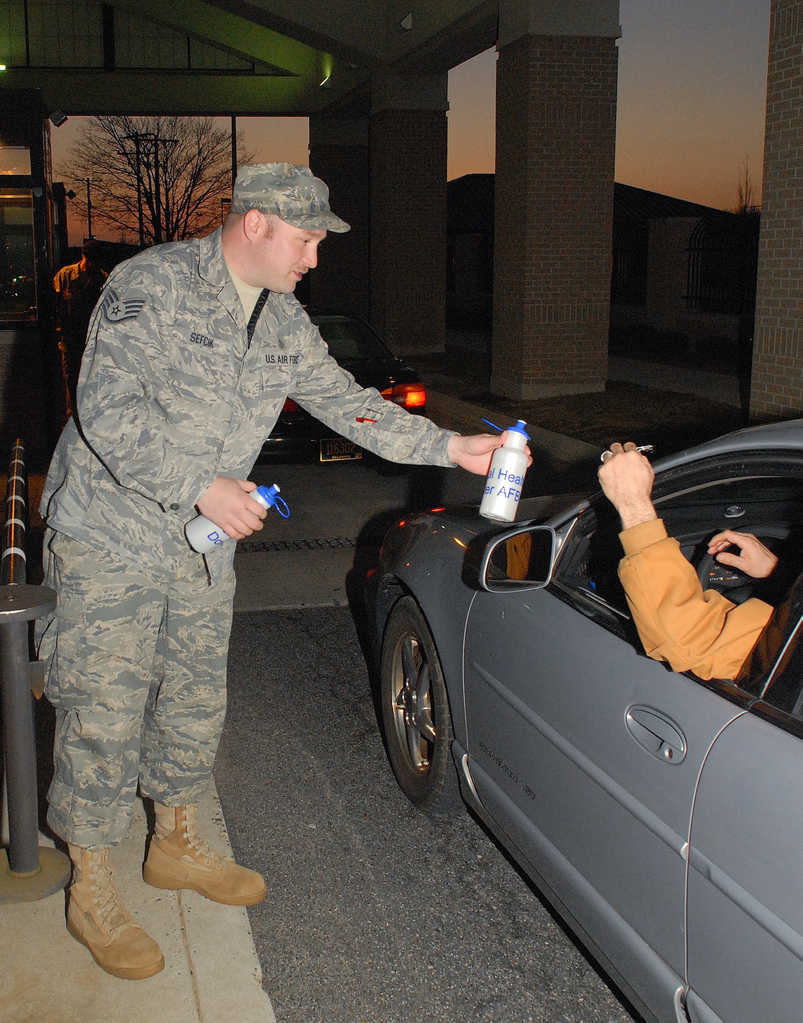 Staff Sgt. Rouven Sefcik, 436th Medical Operations Squadron Alcohol, Drug and Prevention Treatment noncommissioned officer in charge, hands out water bottles March 17, 2011, at the Dover Air Force Base, Del., main gate. The ADAPT program works to keep Team Dover informed on the dangers alcohol and drug misuse. (U.S. Air Force photo by Airman 1st Class Jacob Morgan) 

