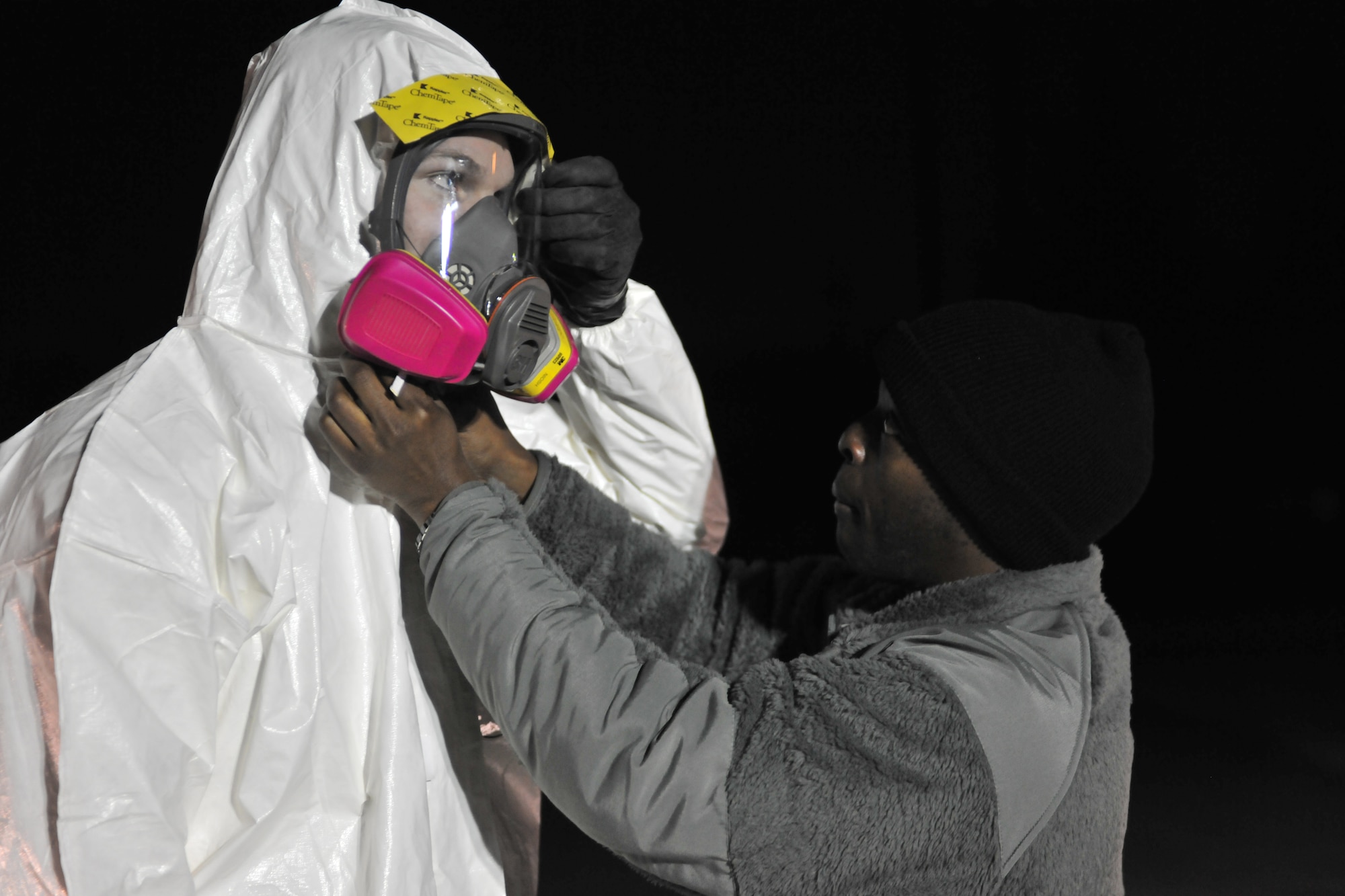 Capt. Isaiah Manigault assists Staff Sgt. Nicholas Sweetman with his chemical protection suit March 20, 2011, at Kadena Air Base, Japan. Sergeant Sweetman was preparing to scan a convoy returning from an urban search and rescue mission in Myagi, Japan. Captain Manigault is the deputy chief of the 18th Aerospace Medicine Squadron Bioenvironmental Engineering Flight, and Sergeant Sweetman is a technician at the 18th AMDS Bioenvironmental Engineering Flight. (U.S. Air Force photo/Master Sgt. Kimberly Spinner) 
