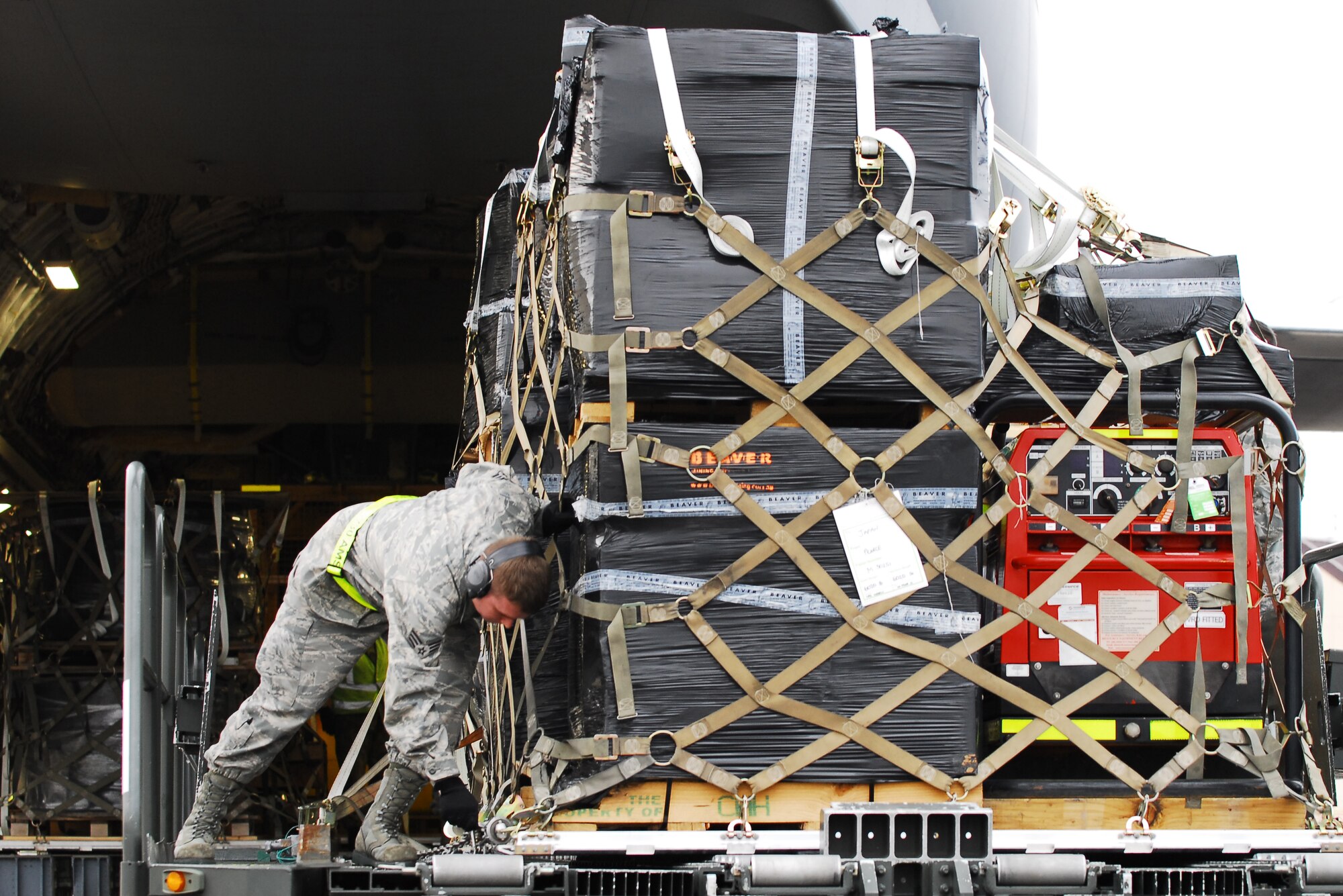 YOKOTA AIR BASE, Japan -- Senior Airman Jack Hunter, 730th Air Mobility Squadron, ramp services technician, tightens down a pallet containing parts for a water cannon system here March 22. A Royal Australian Air Force C-17 Globemaster III delivered the equipment to Yokota. (U.S. Air Force photo/Staff Sgt. Robin Stanchak)