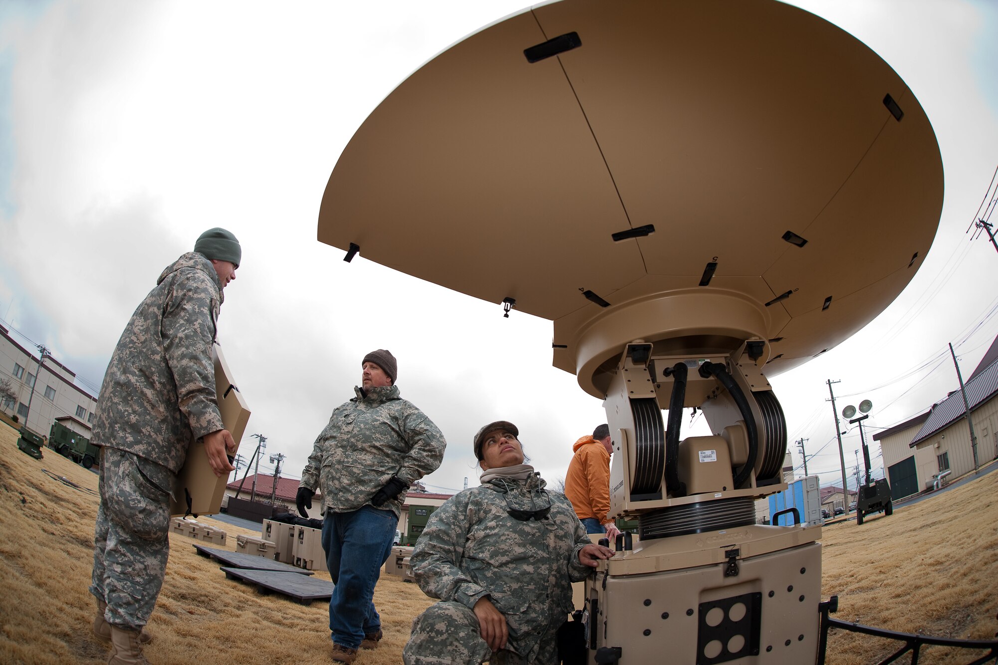 YOKOTA AIR BASE, Japan -- Spc. Sonya Johnson (center), 5th Joint Communications Support Element Pearl Harbor SATCOM, sets up a Hawkeye III,  March 22, to provide high data rate communications for newly erected tents here at Yokota. The tents will serve as additional workspaces for personnel deploying to Yokota in support of Operation Tomodachi. (U.S. Air Force photo/Osakabe Yasuo) 