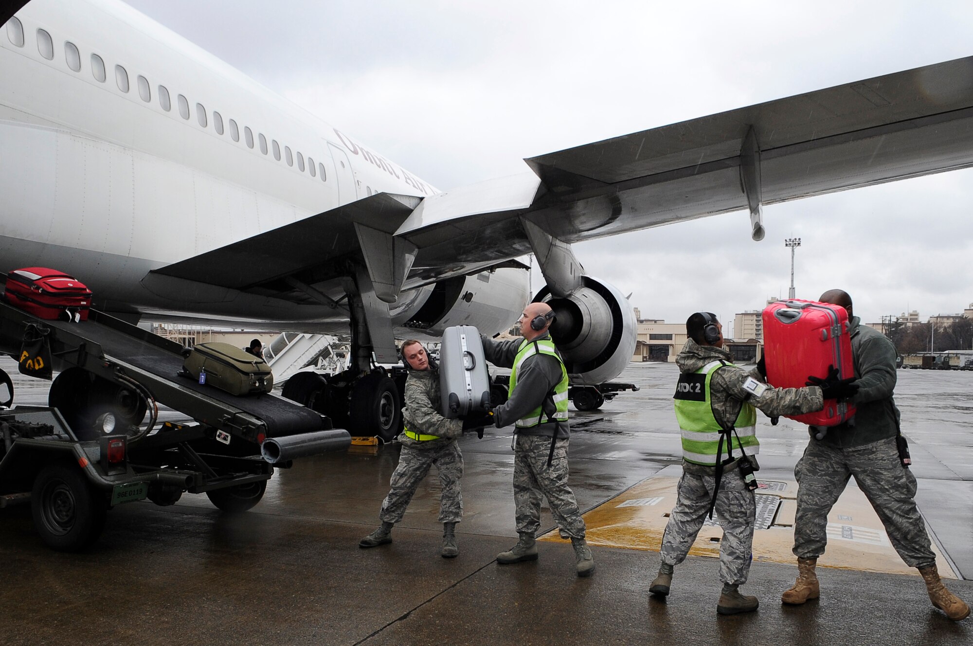 YOKOTA AIR BASE, Japan -- U.S. Air Force Airmen from the 730 Air Mobility Squadron load families' luggage from Fleet Activities Yokosuka, Japan, before they board an aircraft  as part of a voluntary assisted departure March 22, 2011. The Department of State approved the voluntary authorized departure for eligible family members until the situation in Japan has resolved. (U.S. Air Force photo/Master Sgt. Jeromy K. Cross)