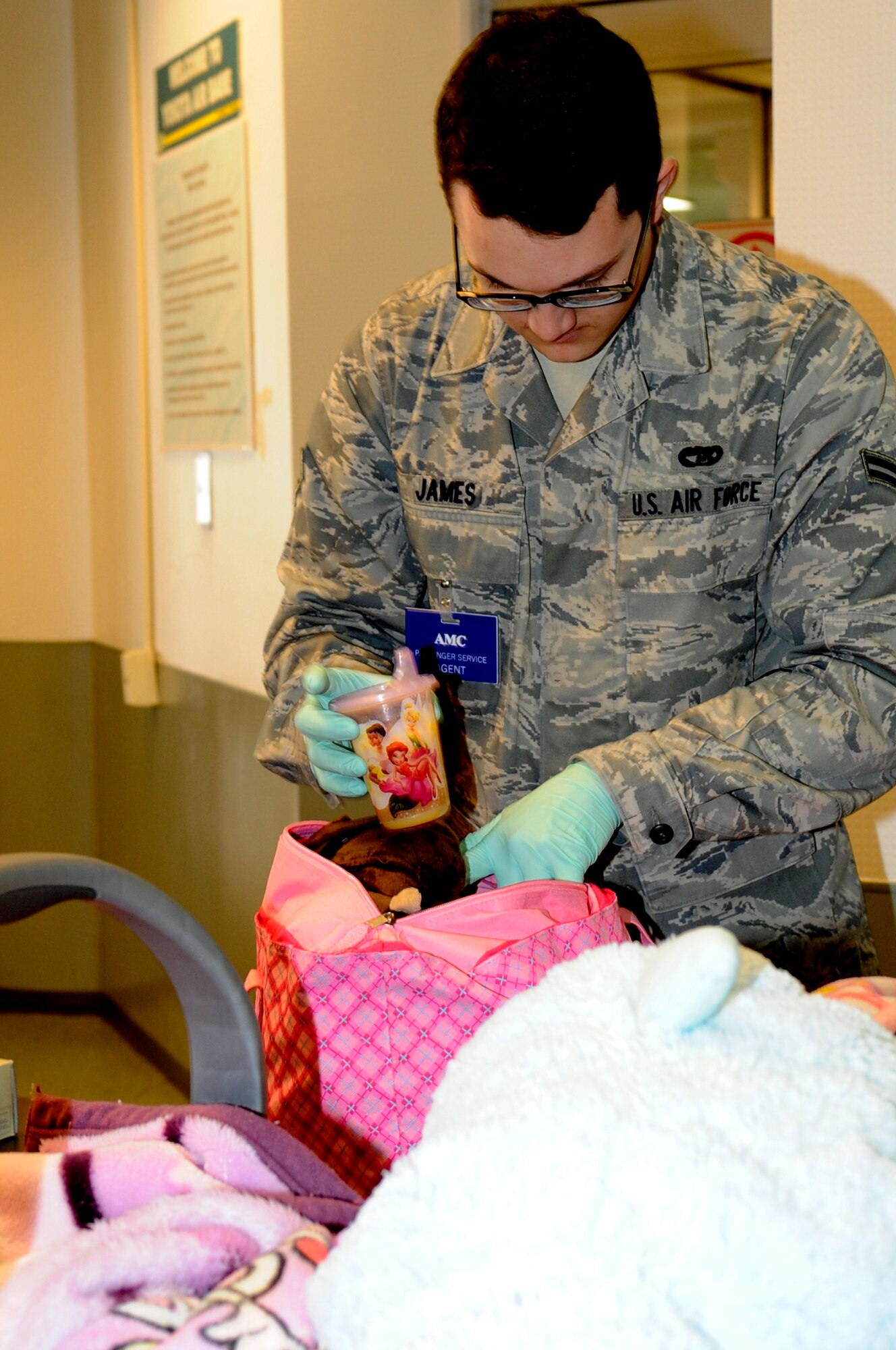YOKOTA AIR BASE, Japan -- Airman First Class Michael James, 730th Air Mobility Squadron, inspects the luggage of families from Fleet Activities Yokosuka, Japan, before they board an aircraft as part of a voluntary assisted departure March 22, 2011.The Department of State approved the voluntary authorized departure for eligible family members until the situation in Japan has resolved. (U.S. Air Force photo/Master Sgt. Jeromy K. Cross)