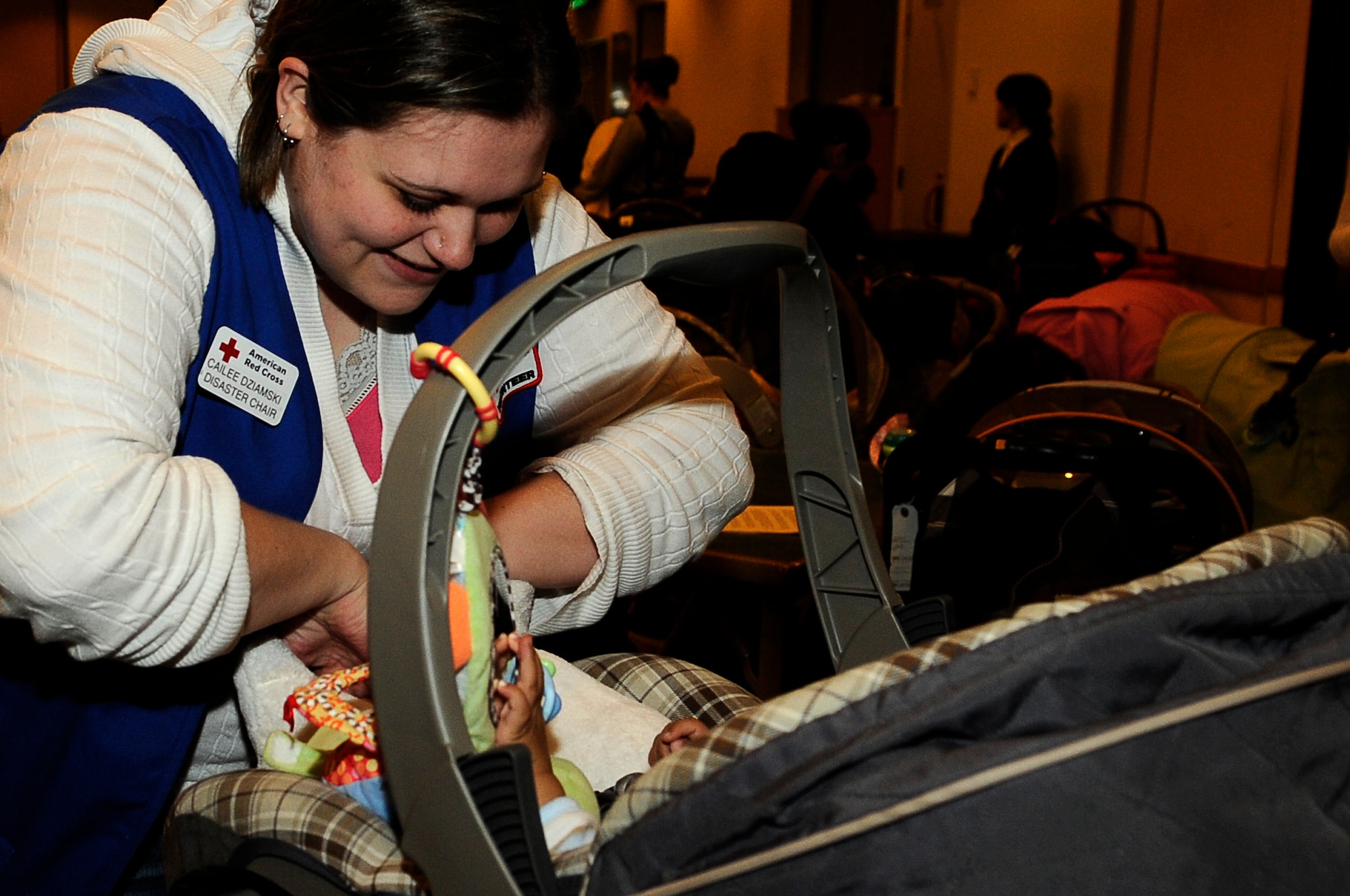 YOKOTA AIR BASE, Japan -- Cailee Dziamski, a Red Cross volunteer, plays with a baby before leaving the Enlisted Club for a voluntary assisted departure, March 22 2011. The Department of State approved the voluntary authorized departure for eligible family members until the situation in Japan has resolved. (U.S. Air Force photo/Master Sgt. Jeromy K. Cross)
