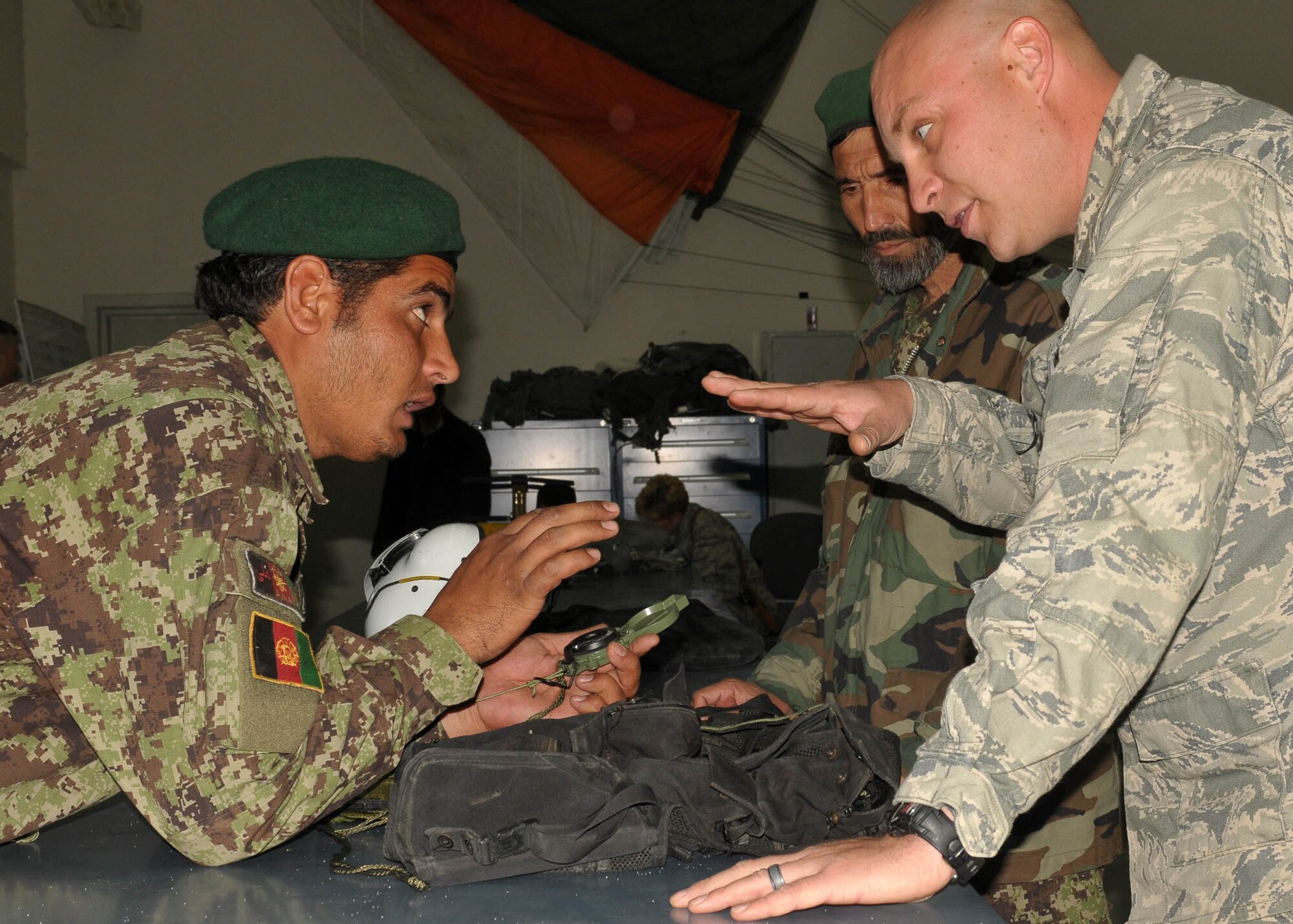 KABUL, Afghanistan - Afghan Air Force member Sgt. Gulbiddin, Life Support Specialist, speaks to Tech. Sgt. Tim Kelso, Aviation Life Support Advisor for the 838th Air Expeditionary Advisory Group, about how to properly use a compass.  (U.S. Navy photo by Mass Communications Specialist 3rd Class Jared E. Walker)