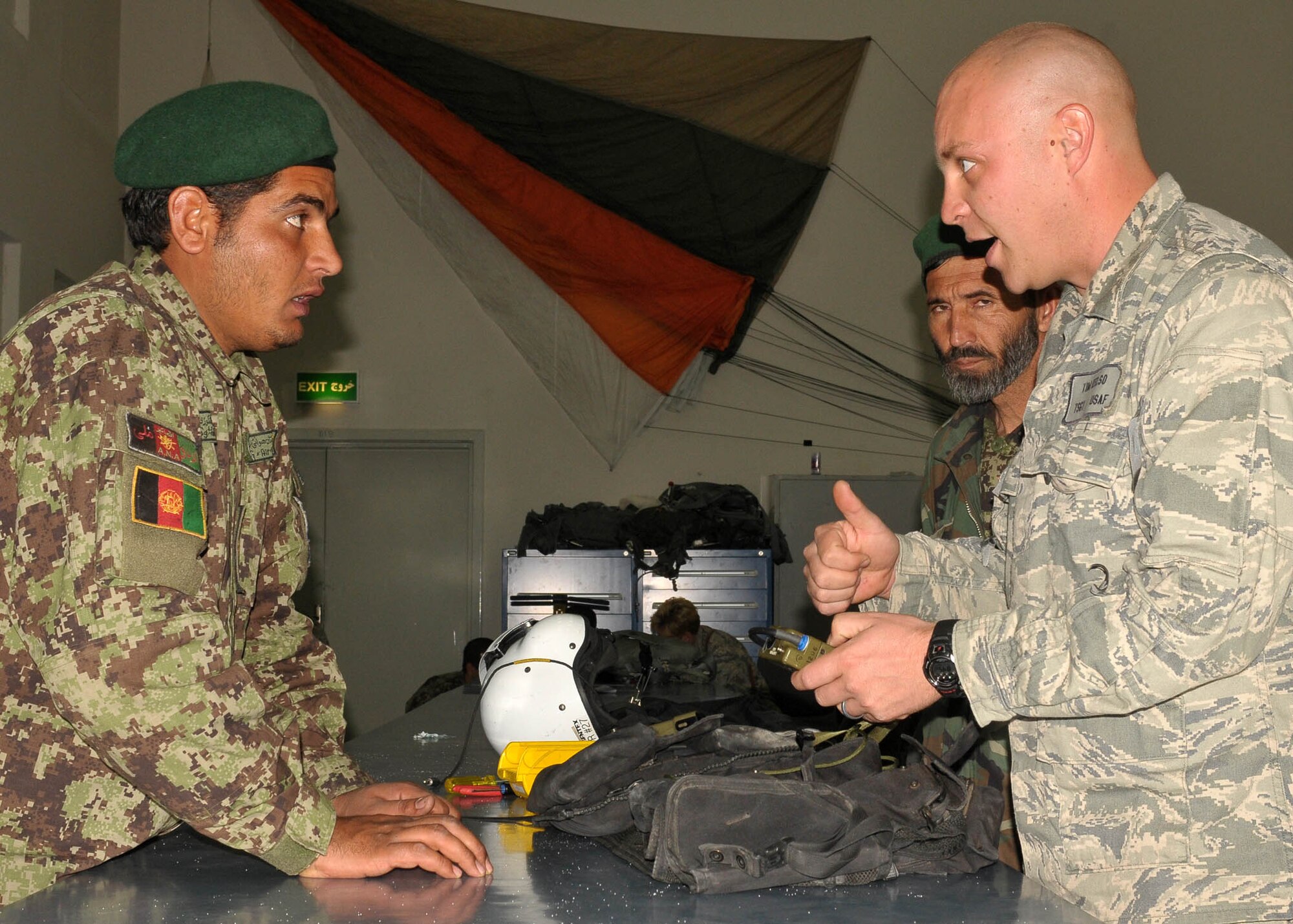 KABUL, Afghanistan - Afghan Air Force member Sgt. Gulbiddin, Life Support Specialist, speaks to Tech. Sgt. Tim Kelso, Aviation Life Support Advisor for the 838th Air Expeditionary Advisory Group, about how to properly use life support equipment.  (U.S. Navy photo by Mass Communications Specialist 3rd Class Jared E. Walker)