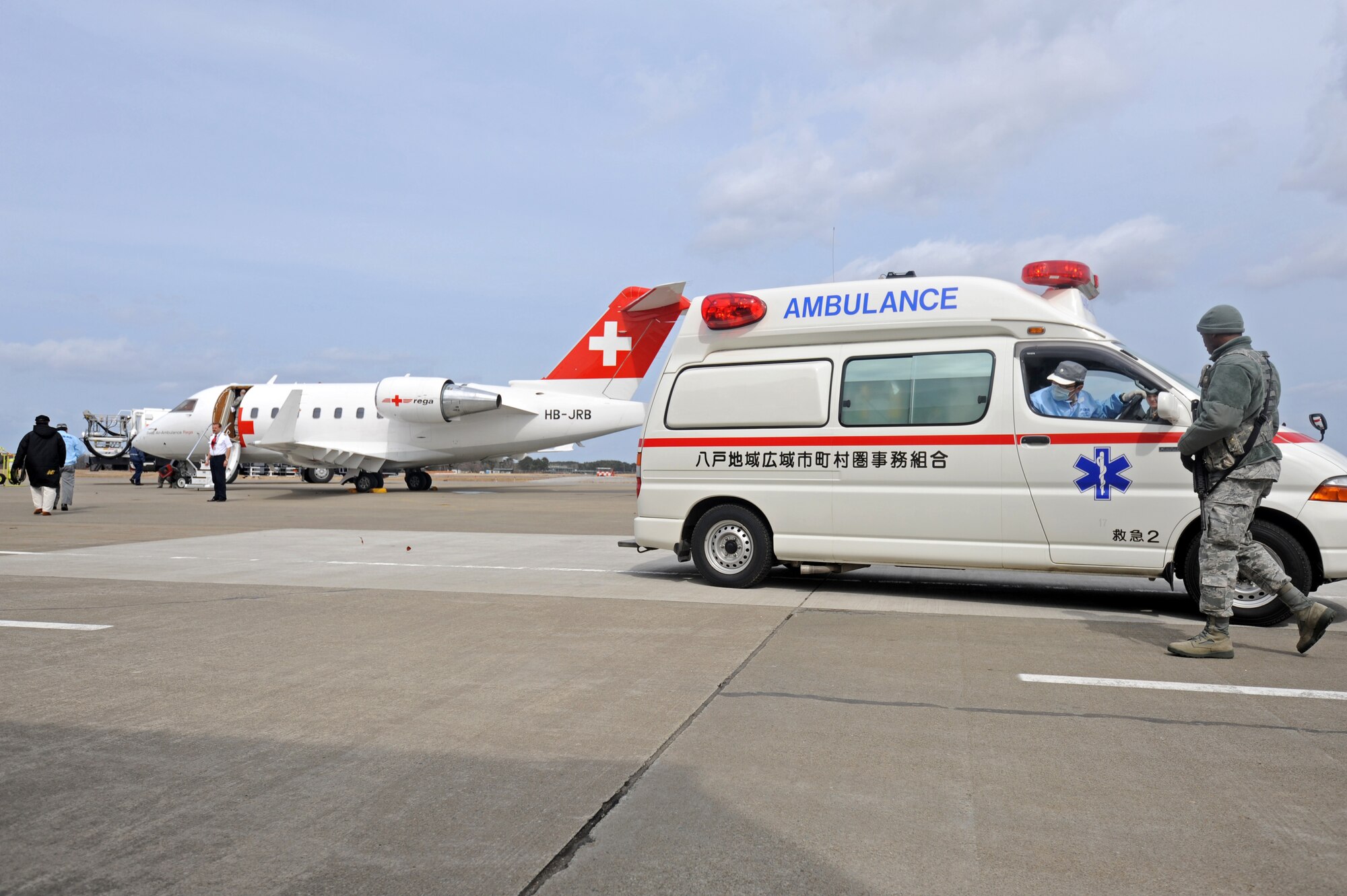 MISAWA AIR BASE, Japan -- The 35th Security forces escort a Hachinohe ambulance onto the base flightline Mar. 21 to allow the transport of Maurer Bruno, a volunteer Swiss Disaster Dog Association member, back to Switzerland. Bruno was helping out for ten days with the recovery efforts in northern Japan prior to his emergency surgery at the Hachinohe Medical Center.   (U.S. Air Force photo by Staff Sgt. April Quintanilla\Released)
