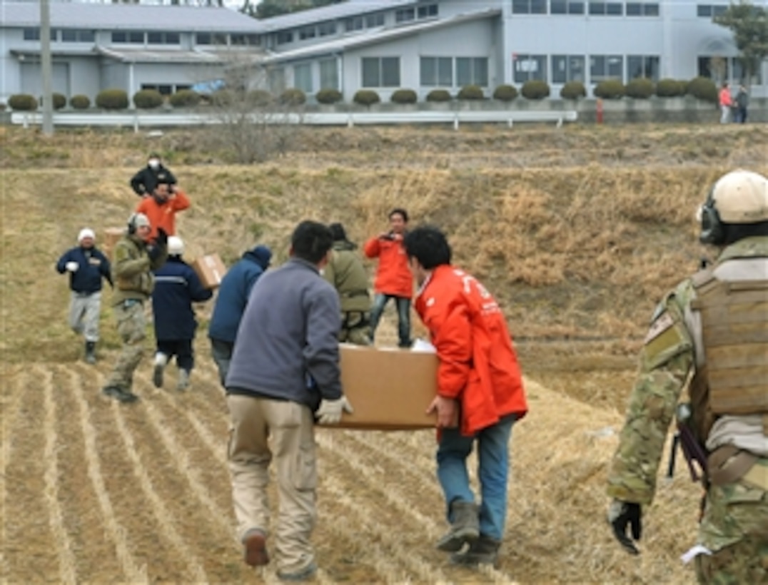 Airmen work alongside a team of Japanese medical workers to unload food, water and medical supplies from a pair of HH-60G Pave Hawk helicopters at Yokota Air Base, Japan, on March 20, 2011.  Airmen from the 33rd Rescue Squadron transported supplies to displaced people in Kessenuma City, in support of Operation Tomodachi, the U.S. military's humanitarian and relief effort in response to the 9.0-magnitude earthquake and tsunami that struck Japan on March 11.  Kessenuma experienced massive destruction from the earthquake and tsunami.  