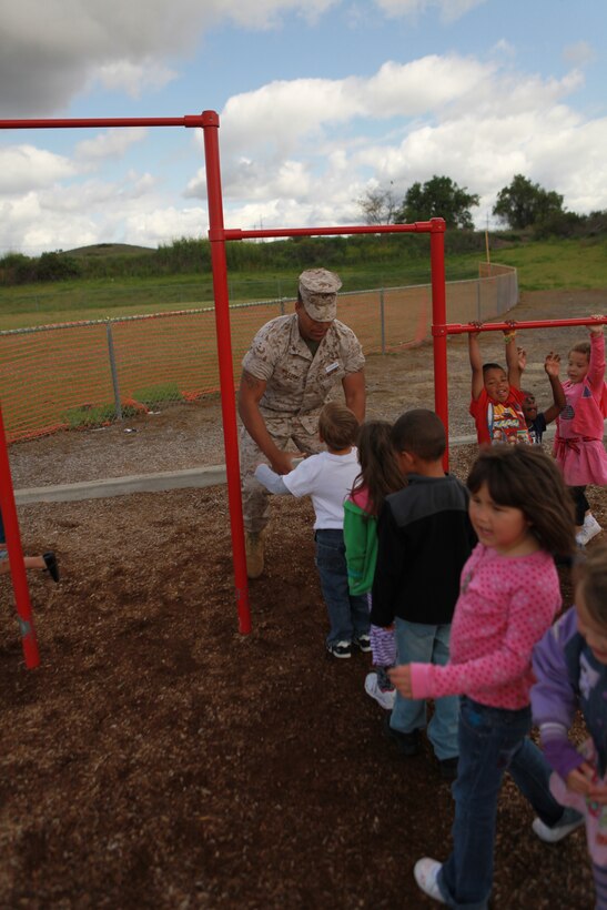 Lance Cpl. Jerrelle L. Williams, an administrative clerk assigned to the 11th Marine Expeditionary Unit, volunteers his time helping kindergarteners perform pull-ups during lunch at an elementary school here Mar. 22. Marines and sailors with the unit spend time every month as part of the unit's commitment to give back to the community.