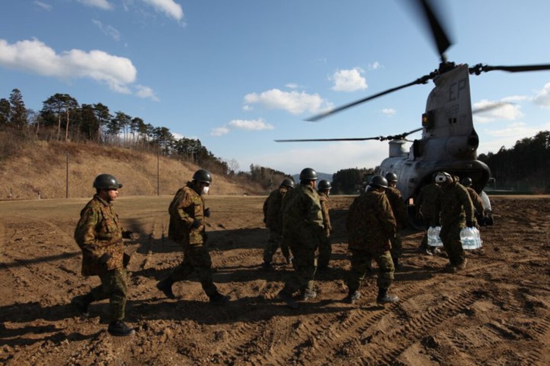 Japan Ground Self-Defense Force Soldiers and Marines from Marine Medium Helicopter Squadron 265, Marine Aircraft Group 36, 1st Marine Air Wing, III Marine Expeditionary Force, unload water, food and toiletries at a distribution site 30 miles north of Sendai March 23. The Government of Japan is leading the relief efforts conducted in Japan. The Marine Corps is actively responding to requests by the Government of Japan to support the humanitarian assistance.