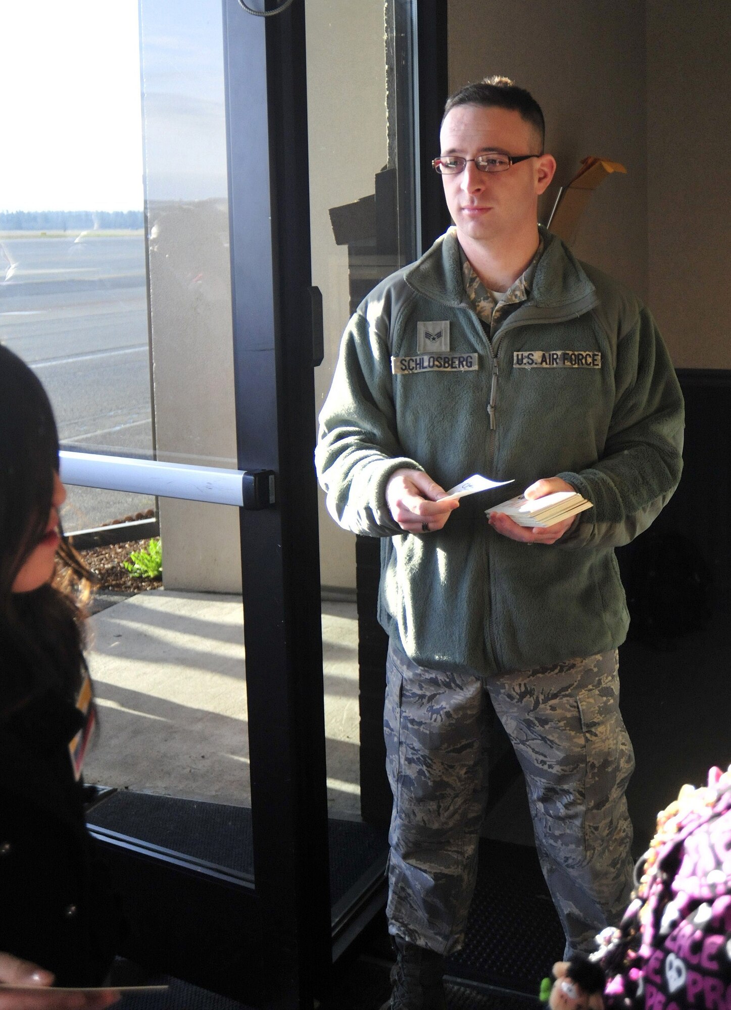 Senior Airman Rory Schlosberg, 62nd Aerial Port Squadron, distributes boarding passes to passengers during a lay-over at Joint Base Lewis-McChord, Wash., March 22, 2011. The Columbian Air Force moved more than 190 passengers from Japan’s Narita International Airport back to Columbia. (U.S. Air Force photo/Airman 1st Class Leah Young)