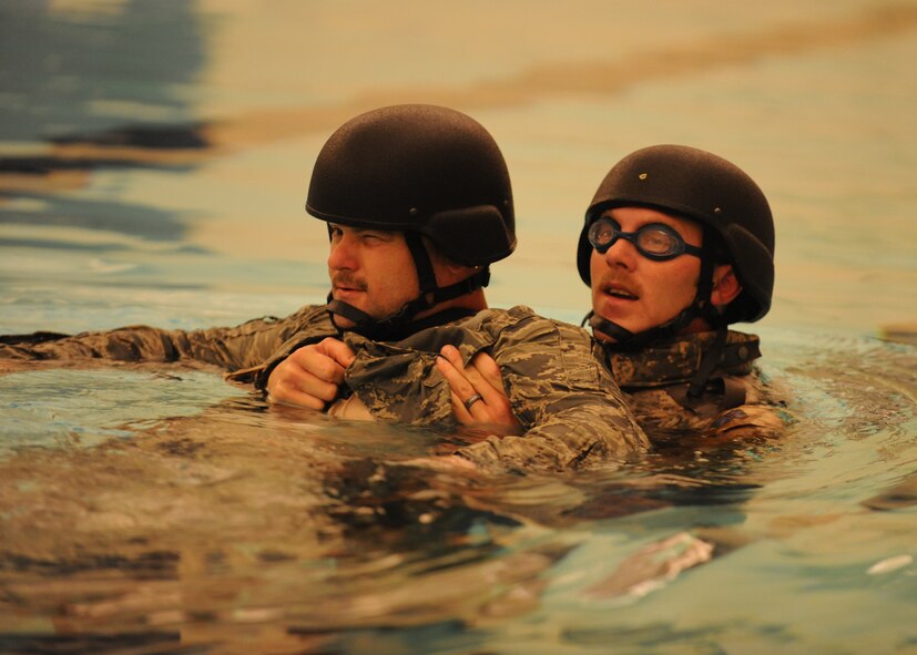 DYESS AIR FORCE BASE, Texas—Senior Airman Joseph Fairchild (back) pulls Master Sgt. Brandon Livingston, 7th Explosive Ordinance Disposal Unit, through water during a two-part training exercise March 22 at the Dyess Fitness Center pool here. The first part involved removing their flak vest while underwater, swimming 25 meters and rescuing each other from the water. The second part involved push-ups, putting together a pan disrupter and carrying it a quarter-mile, all while wearing an 85-pound bomb suit on the track outside of the fitness center.  EOD conducts training everyday so their Airmen are prepared for challenges they may face. (U.S. Air Force photo/ Airman 1st Class Shannon Hall)