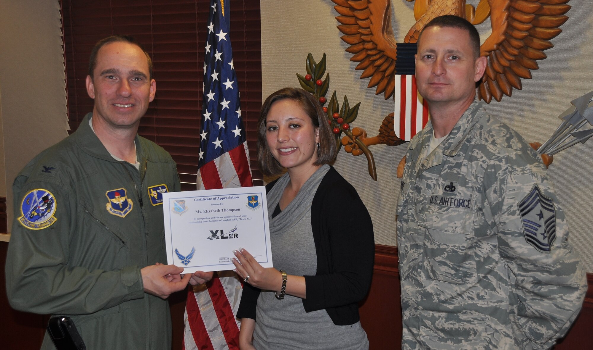 LAUGHLIN AIR FORCE BASE, Texas – Elizabeth Thompson, 47th Comptroller Squadron, poses with Col. Thomas Murphy, 47th Flying Training Wing vice commander, and Chief Master Sgt. Ray DeVite, 47th FTW command chief, after being presented the XLer of the Week award here March 16. The XLer is a weekly award chosen by wing leadership and given to those who consistently make outstanding contributions to Laughlin and their unit. (U.S. Air Force photo by Joel Langton)
