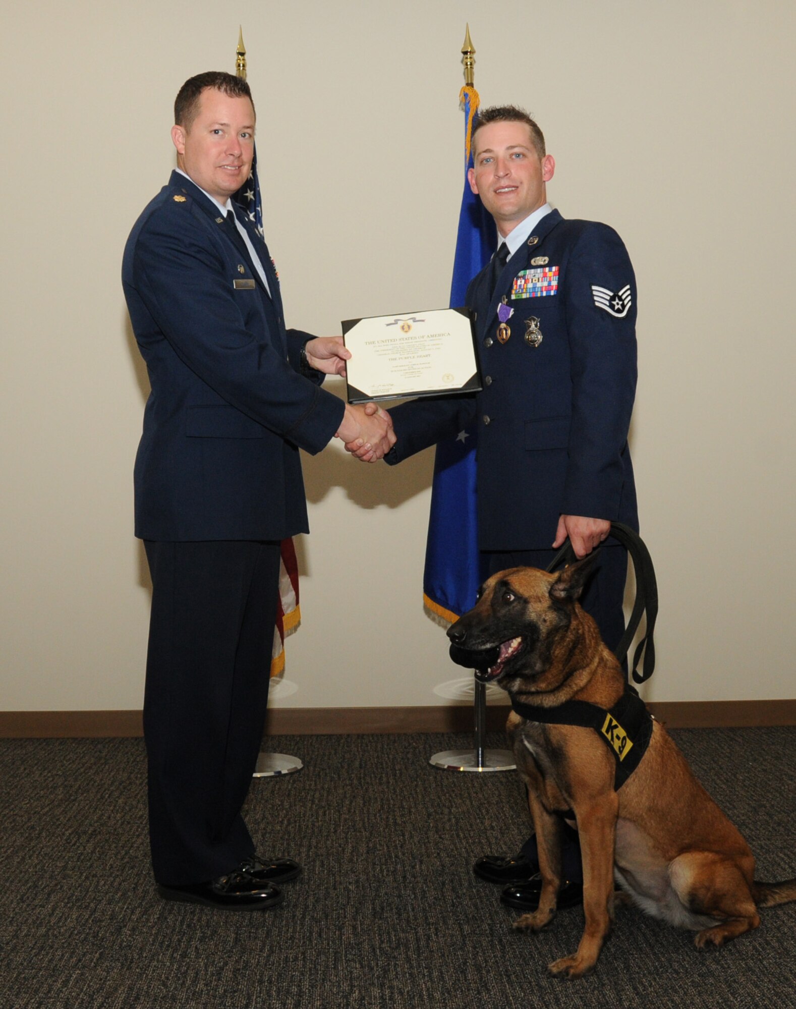 Maj. James Clark, 81st SFS commander, presents a certificate to Sergeant Martin at Friday's Purple Heart ceremony.  Sergeant Martin's military working dog, Densy, is at his side.  (U.S. Air Force photo by Kemberly Groue)