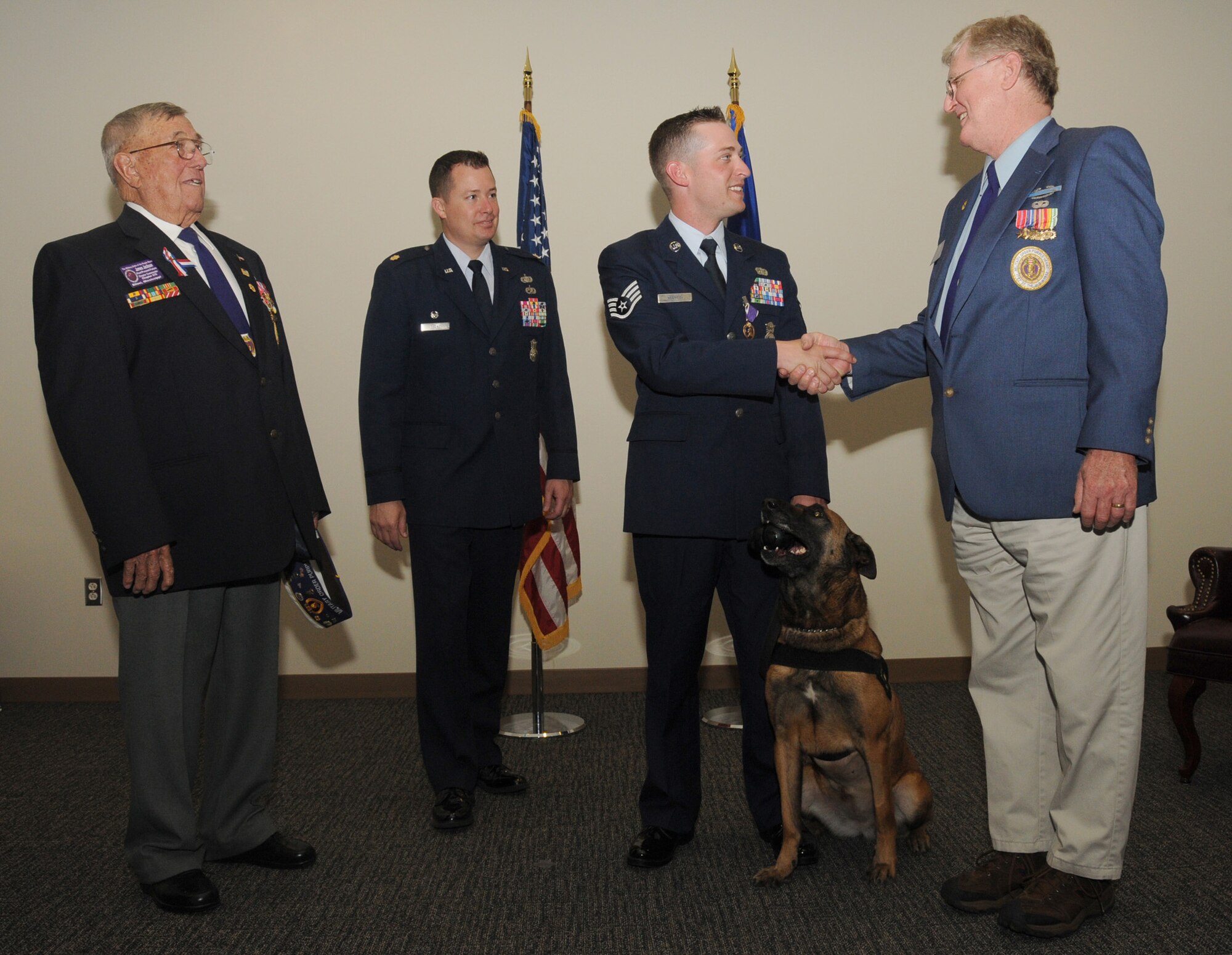 From left, James Jackson, former commander of the Gulf Coast Chapter of the Military Order of the Purple Heart, and Major Clark look on as Sergeant Martin is congratulated
by Mike Bass, current MOPH commander. Sergeant Martin’s military working dog, Densy, sits obediently by his side.  (U.S. Air Force photo by Kemberly Groue)
