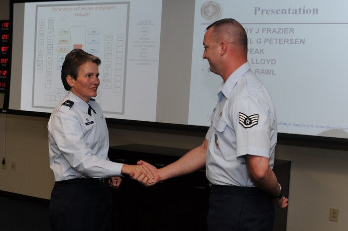 Staff Sgt. Brady Frazier receives a commander's coin from Col. Martha Meeker during the Wing Stand-up March 20 at Joint Base Charleston, S.C.  Sergeant Frazier was possibly preventing a suicide when he noticed signs that an Airman was having difficulties in his personal life. Sergeant Frazier is from the 628th Security Forces Squadron and Colonel Meeker is the Joint Base Charleston commander .  (U.S. Air Force photo/ Staff Sgt. Nicole Mickle)  