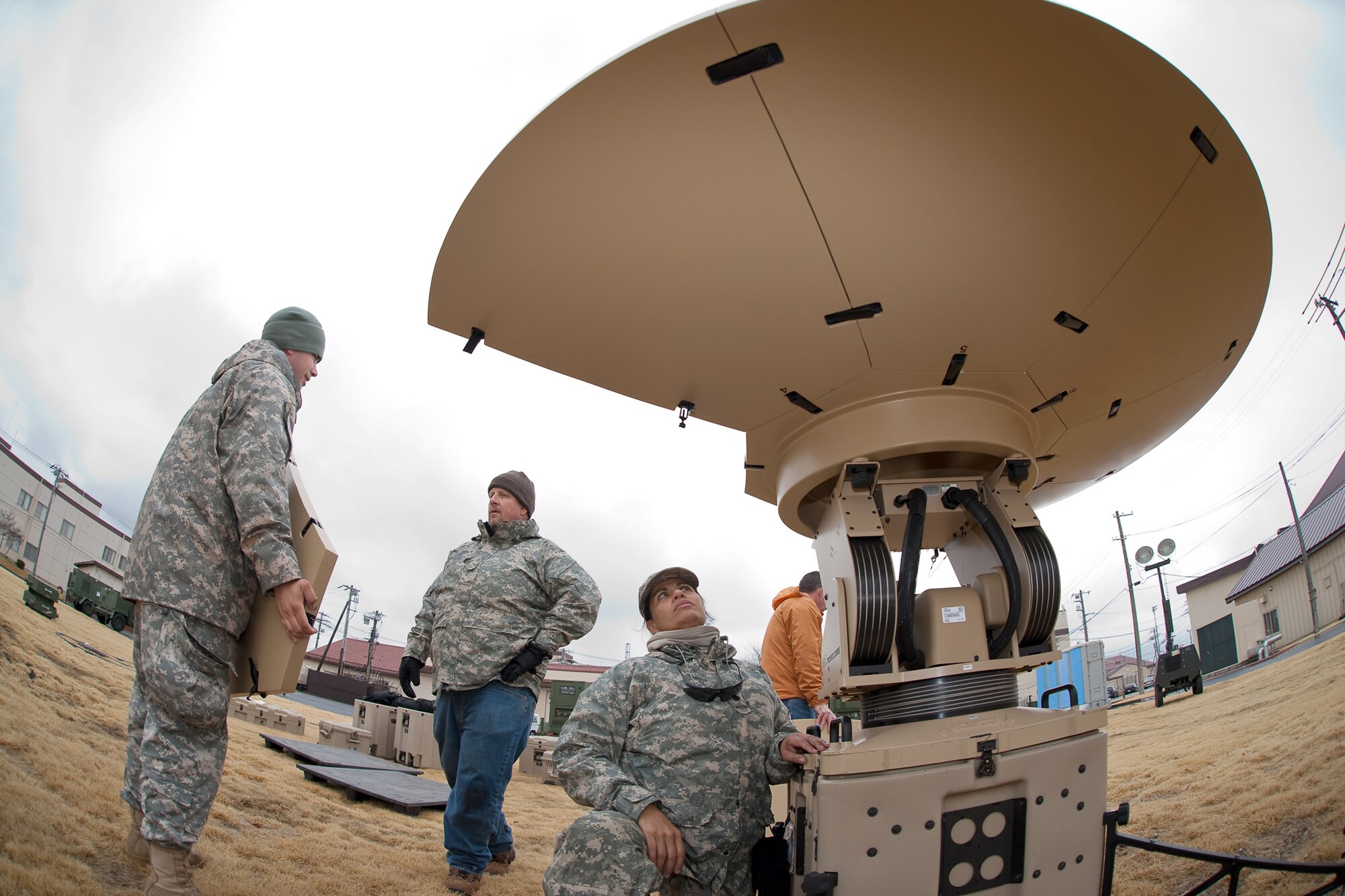 Army Spc. Sonya Johnson (center) sets up a Hawkeye III portable telecommunications system March 22, 2011, at Yokota Air Base, Japan, to provide high-data-rate communications for newly erected tents. The tents will serve as additional workspaces for personnel deploying to Yokot AB in  support of Operation Tomodachi. Specialist Johnson is assigned to the 5th Joint Communications Support Element. (U.S. Air Force photo/Osakabe Yasuo) 