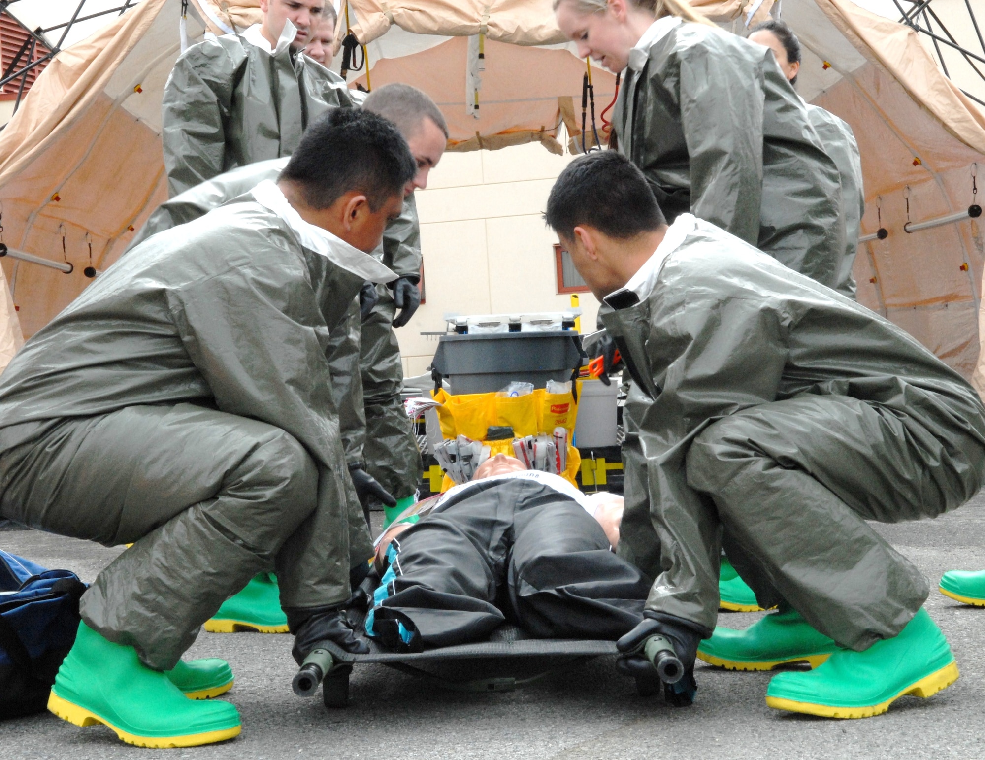 Members of the In-Place Patient Decontamination Team, all from the 95th Medical Group, lift with their legs as they work to treat a dummy “contaminated” with a chemical agent. The Decontamination Team spent March 15 to March 17 receiving in-class instruction about different chemical agents and practicing decontamination procedures. (Air Force photo by Kate Blais)