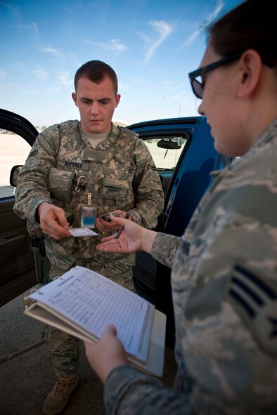 Airman 1st Class Joshua Koerner, 23rd Security Forces Squadron patrolman, hands his government vehicle driver’s license to Senior Airman Jessica Roland, 23rd Operations Support Squadron airfield management shift lead, during an AF Form 483 spot check March 22 on the Moody Air Force Base, Ga., flightline. The spot check was one of many evaluations occurring during a week-long Air Traffic Systems Evaluation Program. (U.S. Air Force photo/Staff Sgt. Jamal D. Sutter)(RELEASED)