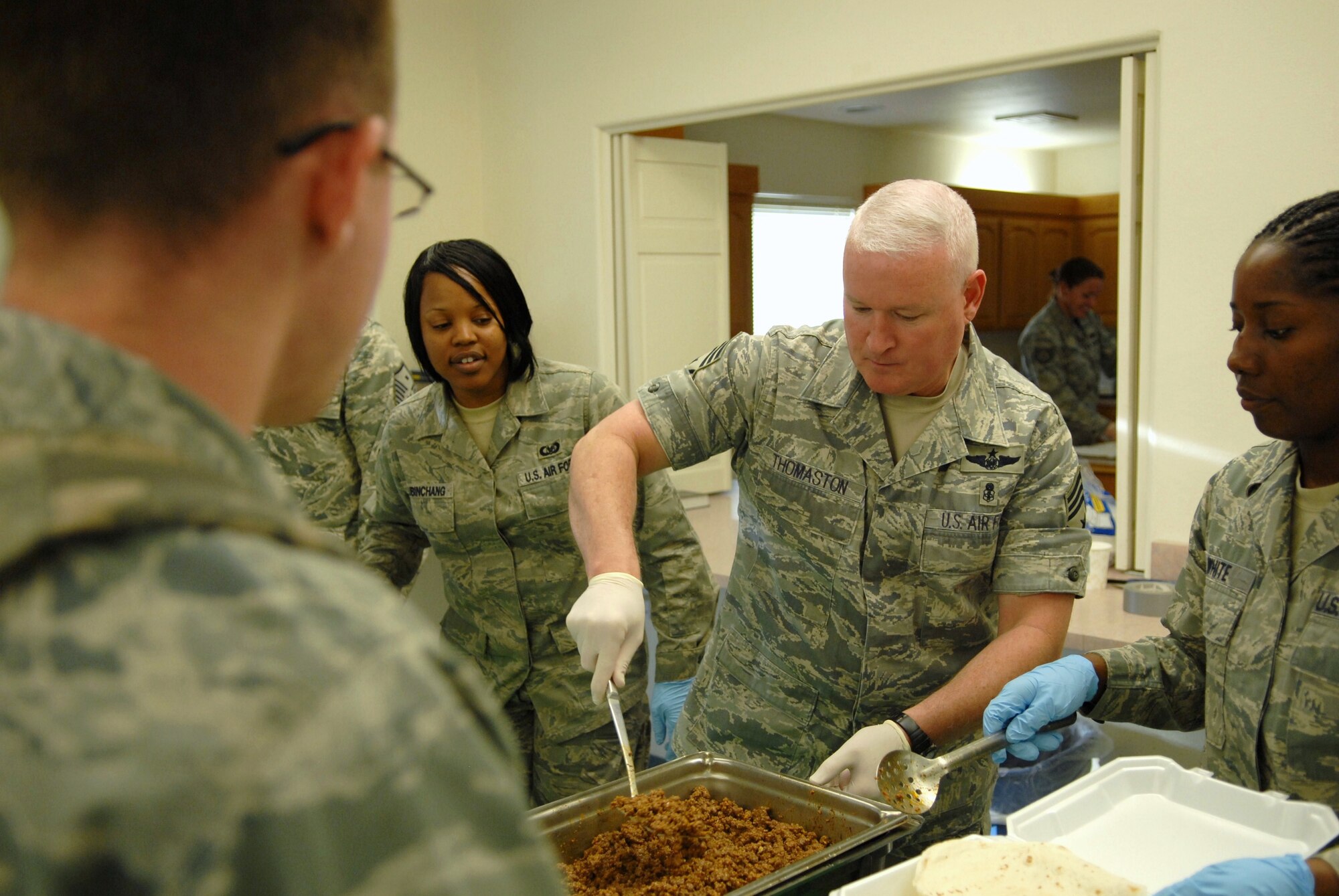 Chief Master Sgt. Bill Thomaston, 95th Air Base Wing command chief, serves up ground beef to an Airman at the Unaccompanied Airmen’s Dinner March 16 at the Chapel 1 Annex. Mexican food was served. Unaccompanied officer and enlisted Airmen were invited to take part in this first-ever event. In the past, the dinners were held exclusively for enlisted Airmen. The purpose of the dinner was to provide a home-cooked meal to unaccompanied Airmen who otherwise may not have healthy eating options. (Air Force photo by Senior Airman William A. O’Brien)