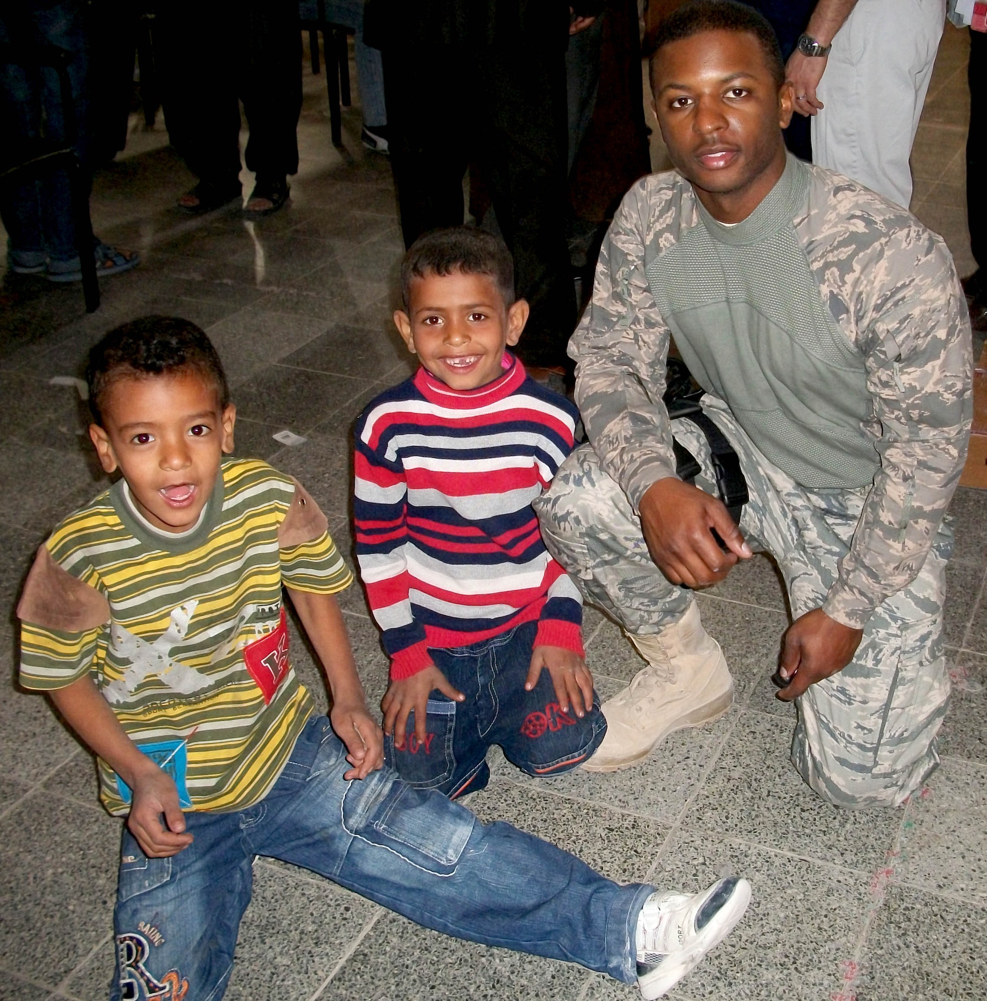Staff Sgt. Kevin Scott Jr. hands kids toys and shoes during a mission Nov. 30, 2010, in Karbala, Iraq. (Courtesy Photo) 
