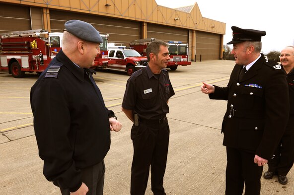 RAF ALCONBURY, United Kingdom - Joe Ruane (right), 423rd Civil Engineer Squadron deputy fire chief, presents a squadron coin to Kevin James (center) March 18 for his support in providing education to the base populace on fire safety and prevention. Mr. James is a local Cambridgshire firefighter. (U.S. Air Force photo by Tech. Sgt. John Barton)