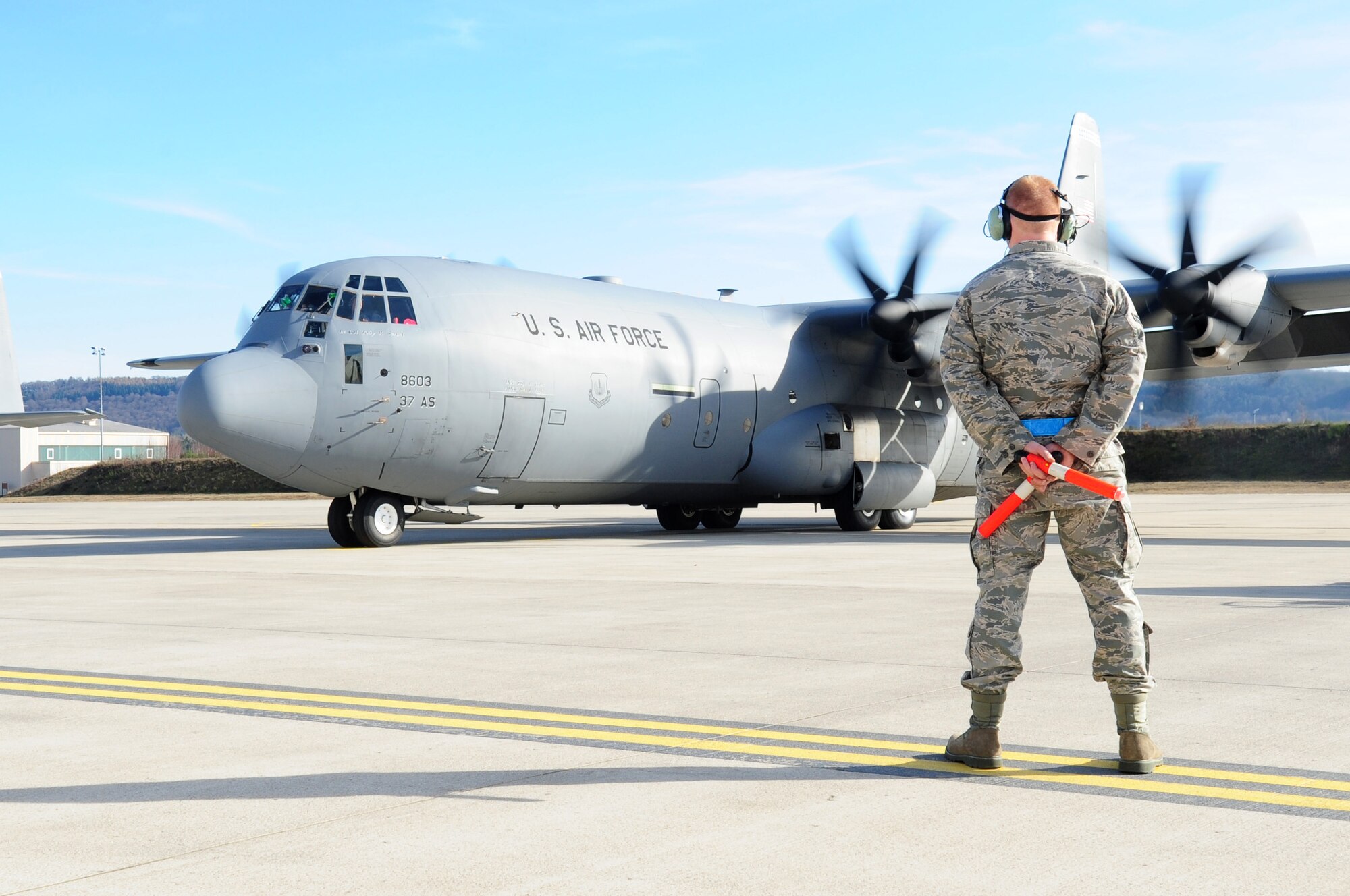 U.S. Air Force Airman 1st Class Eric Cobaugh, 86th Aircraft Maintenance Squadron crew chief, waits to marshal a C-130J en route to support of Joint Task Force Odyssey Dawn, Ramstein Air Base, Germany, March 20, 2011. Joint Task Force Odyssey Dawn is the U.S. Africa Command task force established to provide operational and tactical command and control of U.S. military forces supporting the international response to the unrest in Libya and enforcement of United Nations Security Council Resolution 1973. UNSCR 1973 authorizes all necessary measures to protect civilians in Libya under threat of attack by Qadhafi regime forces. JTF Odyssey Dawn is commanded by U.S. Navy Admiral Samuel J. Locklear, III. (U.S. Air Force photo by Senior Airman Brittany Perry)
