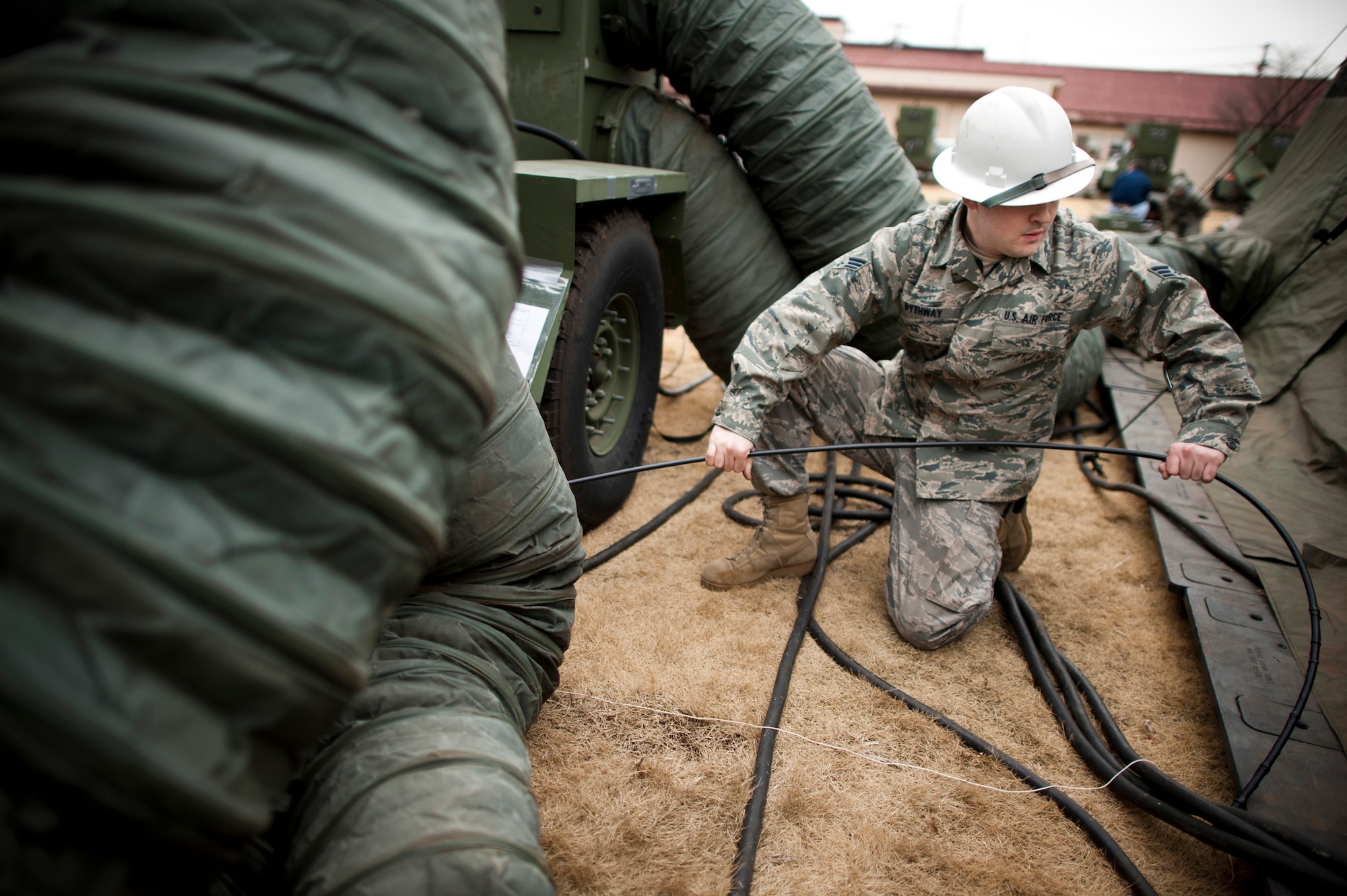 YOKOTA AIR BASE, Japan -- Senior Airman Stephen Bythway, 374th Communications Squadron cable and antenna maintainer, pulls a fiberoptic cable to a communications tent at Yokota Air Base, Japan, March 23. The cabling provided high-speed network access to a new "tent city" of additional office space for military members stationed here temporarily for Operation Tomodachi. (U.S. Air Force photo/Staff Sgt. Samuel Morse)