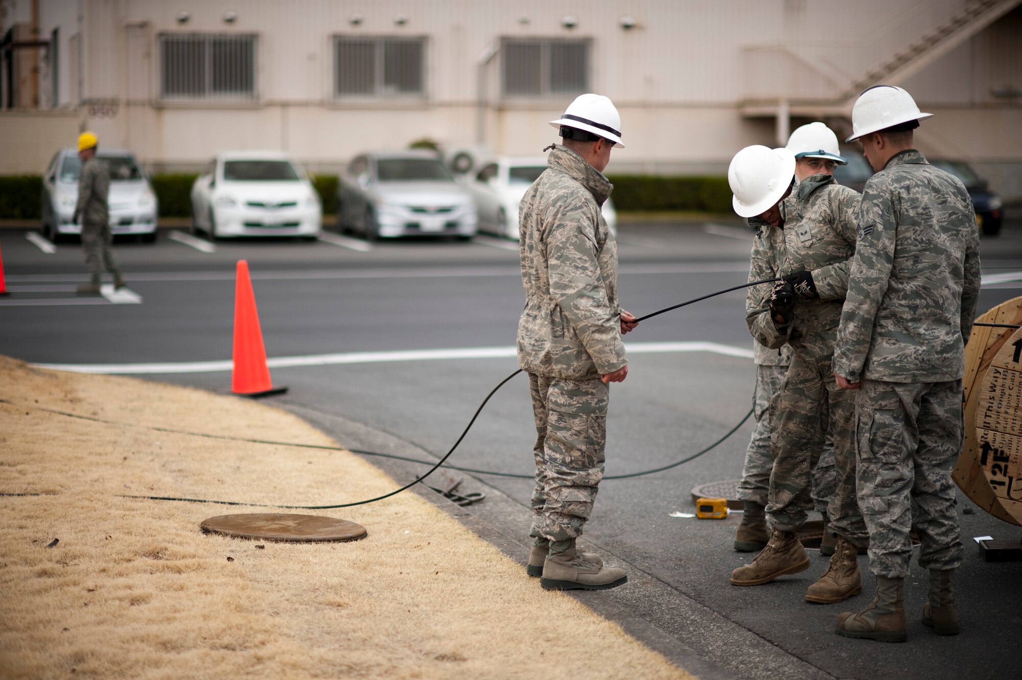 YOKOTA AIR BASE, Japan -- Senior Airman Irvin Johnson, 374th Communications Squadron cable and antenna maintainer, cuts a length of fiberoptic cable off of a reel at Yokota Air Base, Japan, March 23. The cabling provided high-speed network access to a new "tent city" of additional office space for military members stationed here temporarily for Operation Tomodachi. (U.S. Air Force photo/Staff Sgt. Samuel Morse)