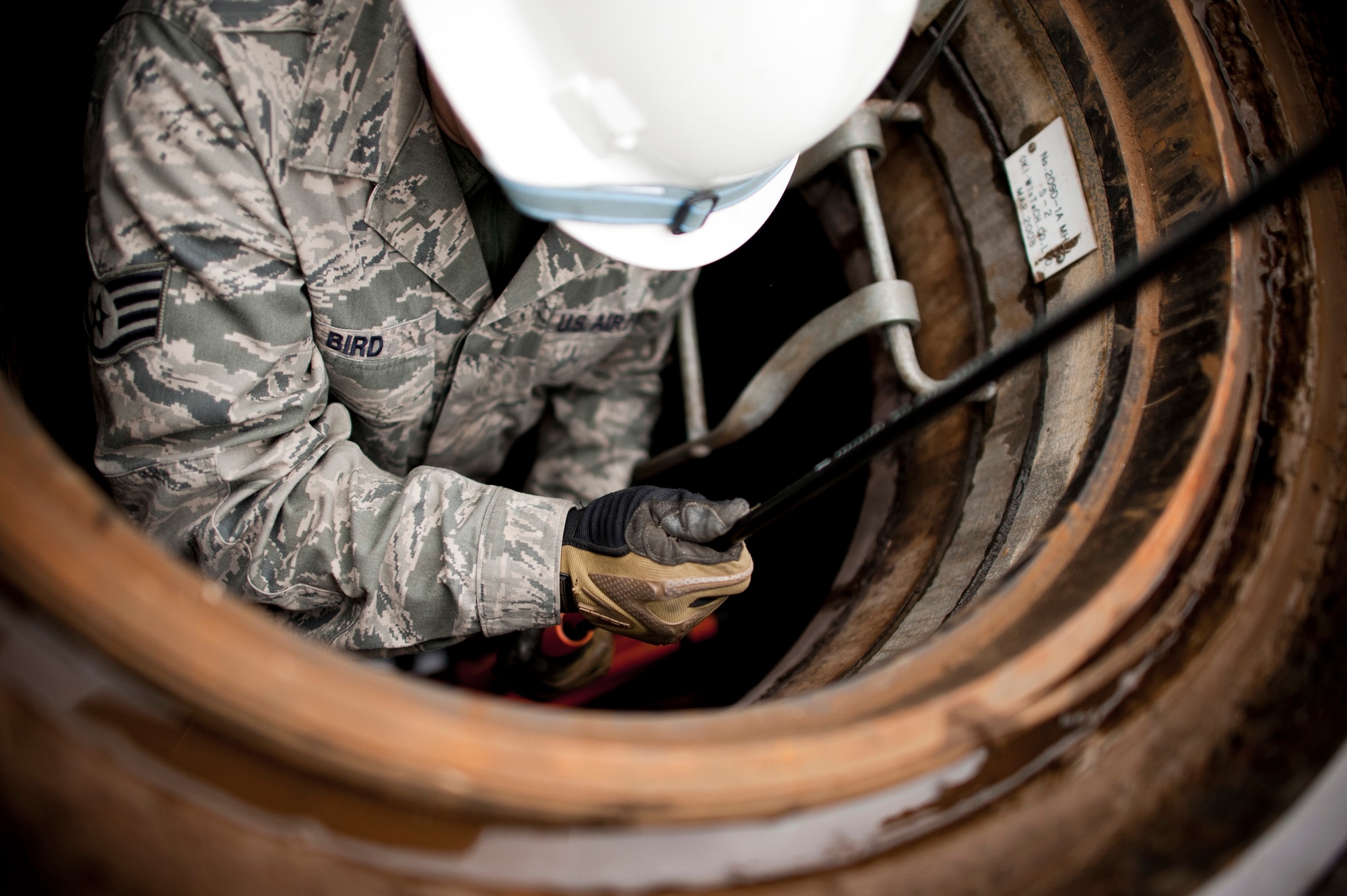 YOKOTA AIR BASE, Japan -- Staff Sgt. Steven Bird, 374th Communications Squadron cable and antenna maintainer, threads a fiberoptic cable through an underground conduit at Yokota Air Base, Japan, March 23. The cabling provided high-speed network access to a new "tent city" of additional office space for military members stationed here temporarily for Operation Tomodachi. (U.S. Air Force photo/Staff Sgt. Samuel Morse)