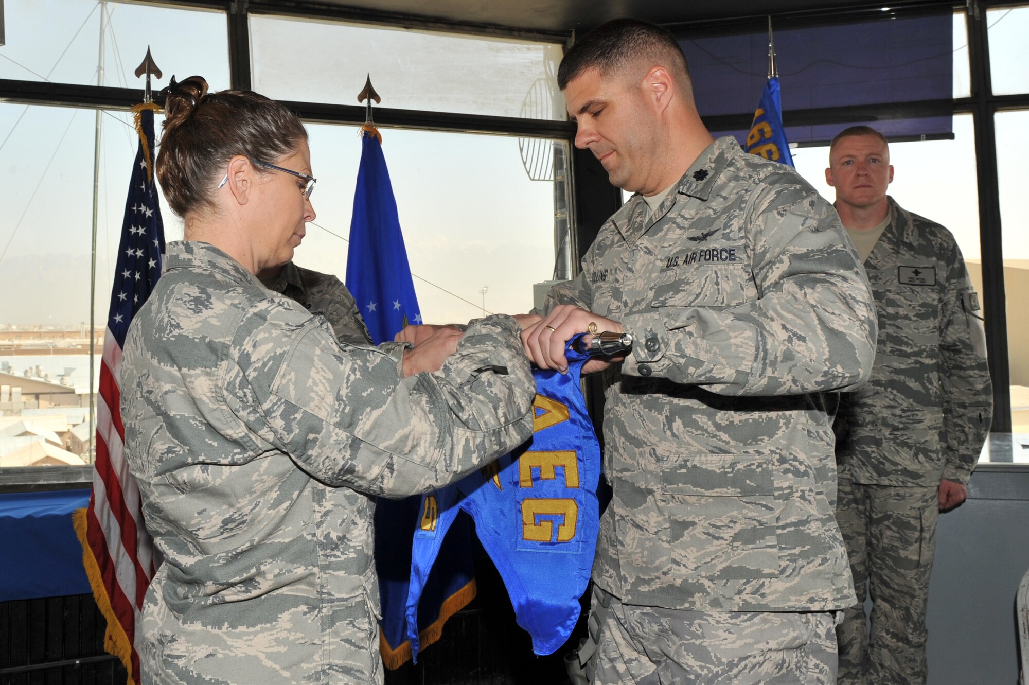 Col. Lesa Toler, 466th Air Expeditionary Group commander, and Lt. Col. Jeffrey Collins, 766th  Air Expeditionary Squadron commander, rolls the guidon as Lt. Col. Collins relinquishes command during the 766th AES inactivation ceremony at Bagram Airfield, Afghanistan, March 23, 2011. Colonel Collins will assume command of the 966th Air Expeditionary Squadron. (U.S. Air Force photo by Senior Airman Sheila deVera)