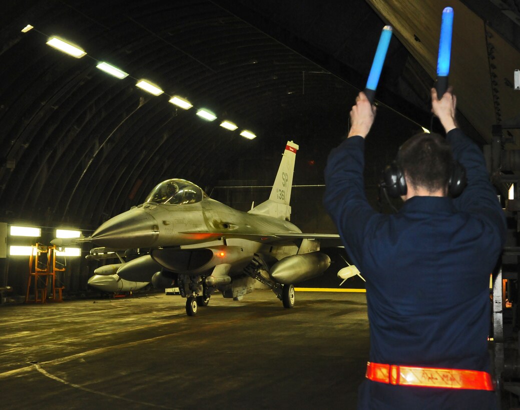 SPANGDAHLEM AIR BASE, Germany – A crew chief from the 52nd Aircraft Maintenance Squadron marshals an F-16 Fighting Falcon out of a hardened aircraft shelter here in support of Operation Odyssey Dawn March 20. Joint Task Force Odyssey Dawn is the U.S. Africa Command task force established to provide operational and tactical command and control of U.S. military forces supporting the international response to the unrest in Libya and enforcement of United Nations Security Council Resolution (UNSCR) 1973. UNSCR 1973 authorizes all necessary measures to protect civilians in Libya under threat of attack by Qadhafi regime forces.  JTF Odyssey Dawn is commanded by U.S. Navy Admiral Samuel J. Locklear, III. (U.S. Air Force photo/Staff Sgt. Benjamin Wilson)