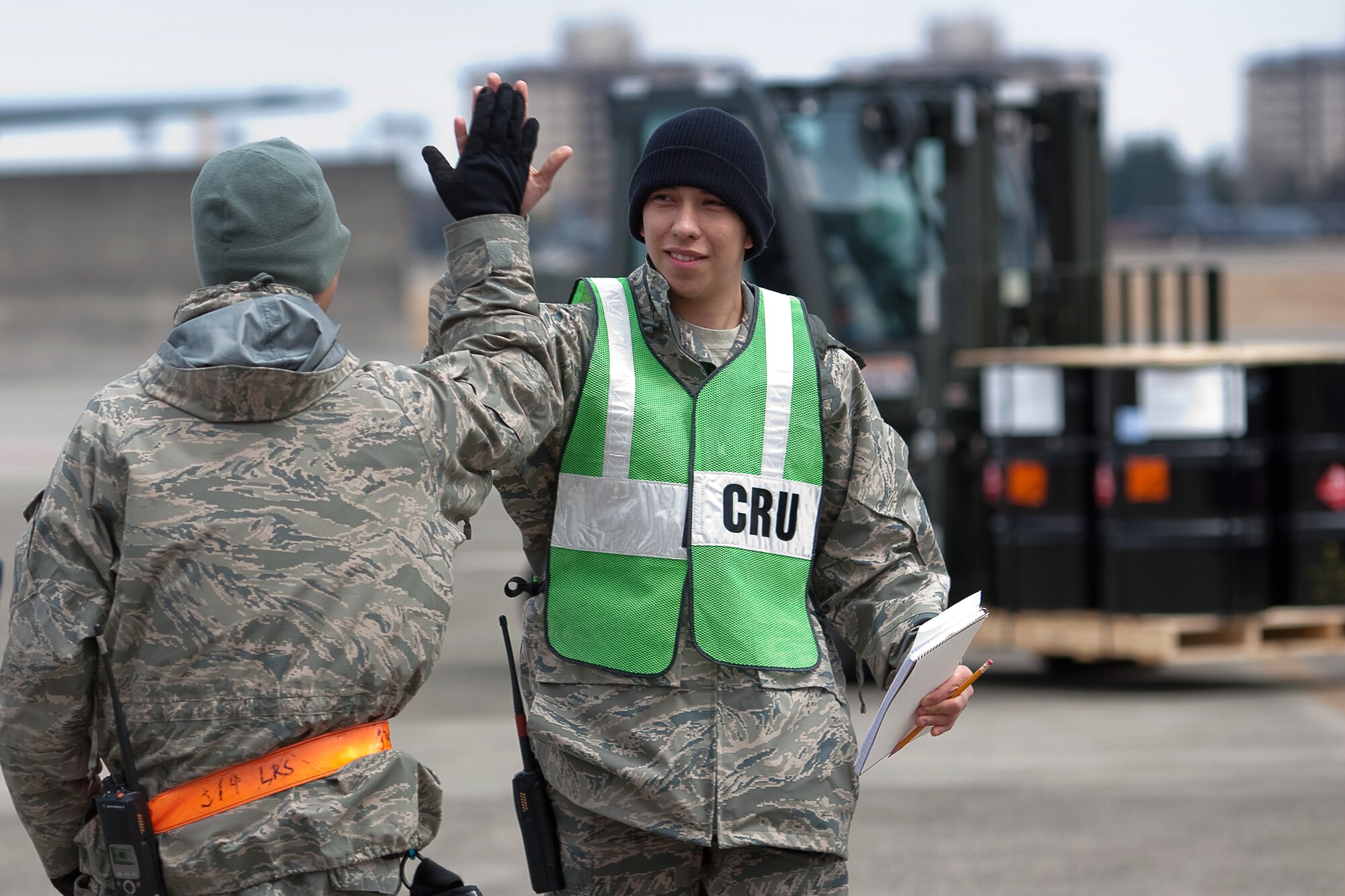 YOKOTA AIR BASE, Japan -- Airman 1st Class Isaac Perez (right), 374th Maintenance Squadron, and Senior Airman Stanley Quach, 374th Logistics Readiness Squadron, work together to help load 116 pallets of diesel fuel onto 16 Japanese trucks at Yokota Air Base March 23.  The 374th LRS prepared the fuel for shipment to the Caterpillar factory in Sagamihara. The plant, which employees thousands and manufactures equipment critical to the rebuilding of Japan, currently runs on generator power. (U.S. Air Force photo/Osakabe Yasuo) 