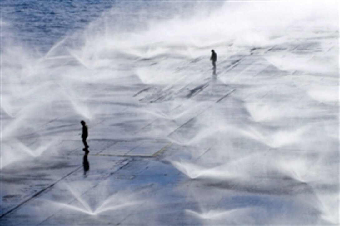 U.S. Navy sailors aboard the aircraft carrier USS Ronald Reagan monitor wash down system sprinklers on the flight deck in the Pacific Ocean, March 23, 2011. Sailors scrubbed the external surfaces on the flight deck to remove potential radiation contamination. The Ronald Reagan is operating off the coast of Japan providing humanitarian assistance as directed to support Operation Tomodachi.