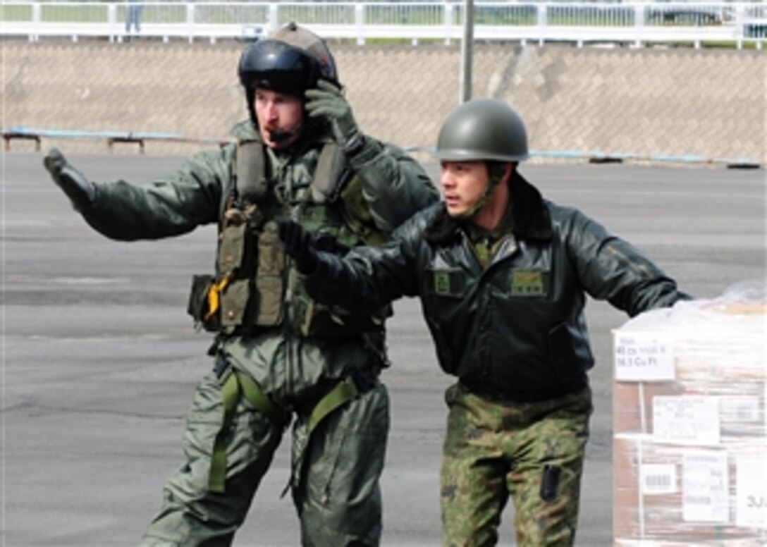 Gunnery Sgt. Sam Carnes (left) and a member of the Japan Maritime Self-Defense Force direct the movement of humanitarian assistance and disaster relief supplies unloaded from a CH-46E Sea Knight helicopter assigned to Marine Medium Helicopter Squadron 262, embarked aboard the amphibious assault ship USS Essex (LHD 2) on March 22, 2011.  The Essex is operating off the coast of Hachinohe in northeastern Japan in support of Operation Tomodachi.  