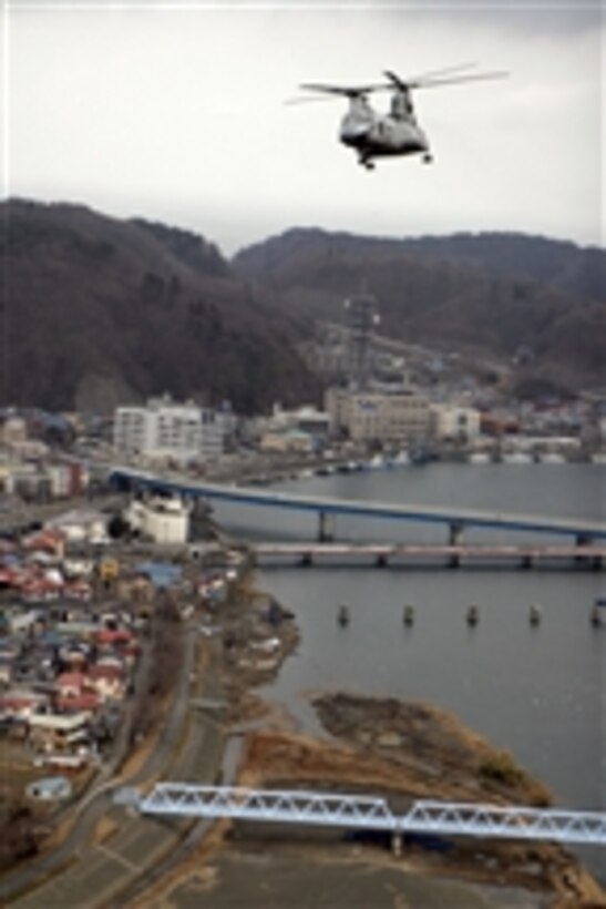 A CH-46E Sea Knight helicopter with Marine Medium Helicopter Squadron 262 (Reinforced), 31st Marine Expeditionary Unit, flies over Miyako, Japan, on March 21, 2011.  The helicopter is carrying water and blankets to aid those affected by the 9.0 earthquake and subsequent tsunami that ravaged the region.  
