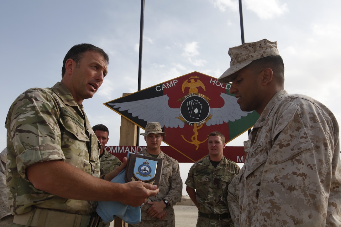 Royal Air Force Warrant Officer John Taylor presents Maj. Jose Lopez with a Royal Air Force Tactical Supply Wing plaque commemorating the coalition partnership between the Tactical Support Wing and Marine Wing Support Squadron 373, during a ceremony at the at the support squadron’s compound on Camp Leatherneck, Afghanistan, March 24. The two support units worked hand-in-hand during Operation Rawhide II. Taylor is the detachment commander for the Tactical Support Wing and Lopez is the operations officer for MWSS-373.