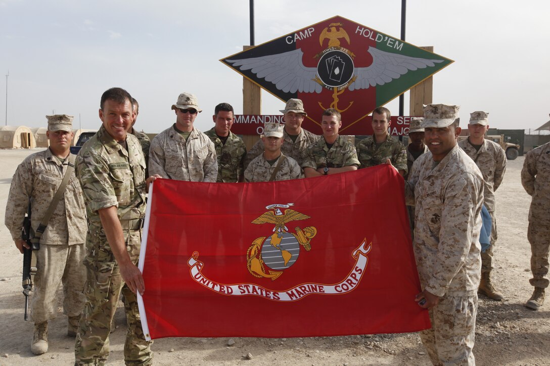 Royal Air Force Warrant Officer John Taylor, left, and Maj. Jose Lopez display a Marine Corps flag, a gift from Marine Wing Support Squadron 373 to the Royal Air Force Tactical Supply Wing, during a ceremony commemorating the two unit's coalition partnership at the support squadron's compound on Camp Leatherneck, Afghanistan, March 24. The two support units worked hand in hand during Operation Rawhide II. Taylor is the detachment commander for Tactical Supply Wing and Lopez is the operations officer for MWSS-373.